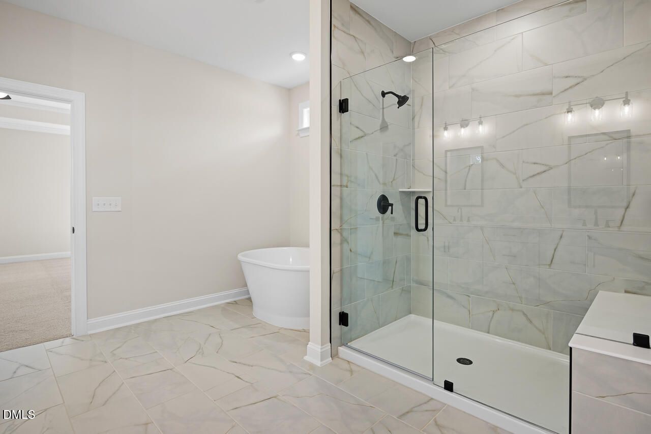 Modern primary bathroom with freestanding tub and glass walk-in shower in Davidson Homes Crawford D, Wake Forest, NC