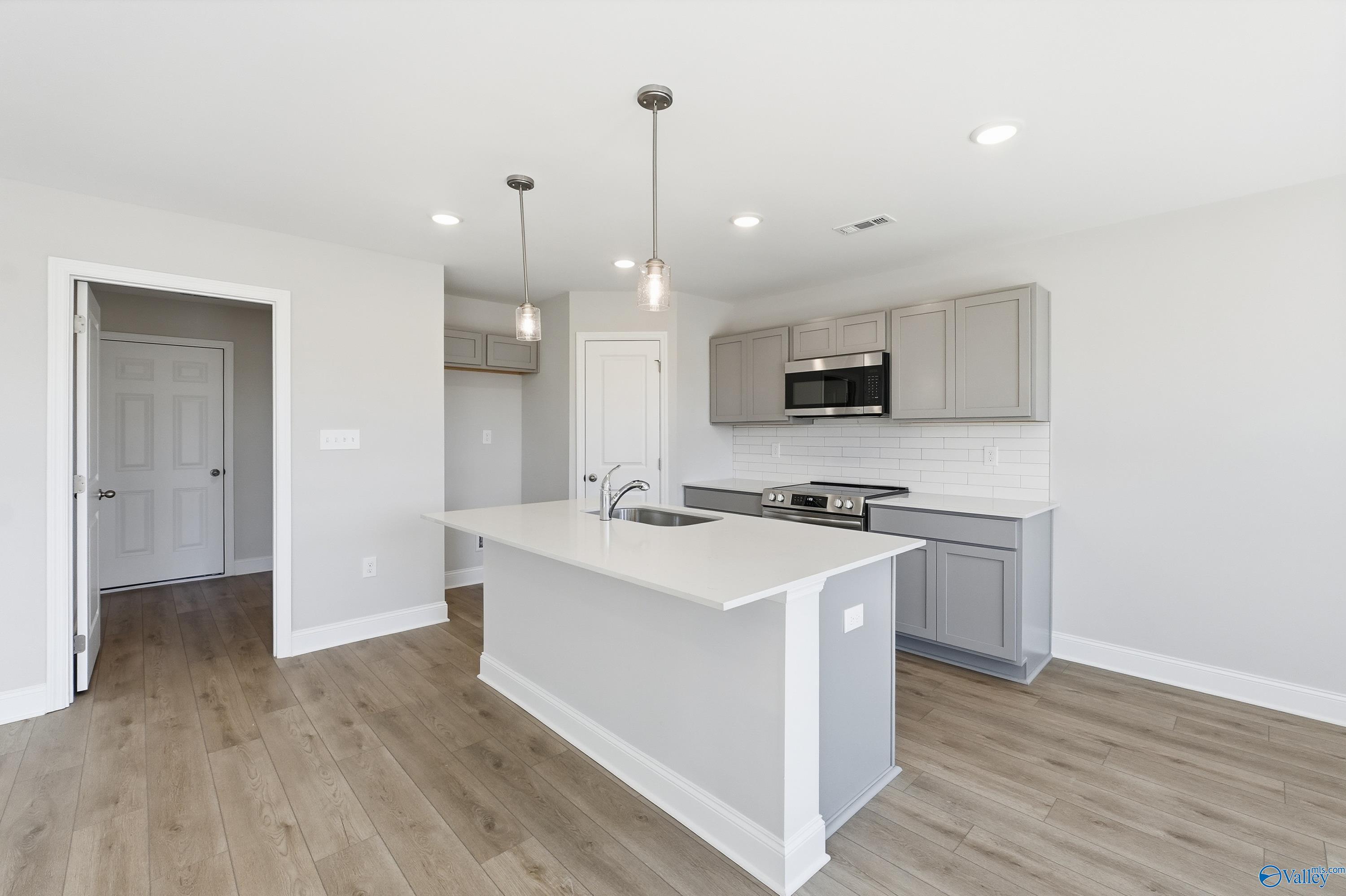 Modern kitchen featuring white quartz island, stainless steel range, and pendant lights in Davidson Homes The Butler floor plan, New Market, Alabama