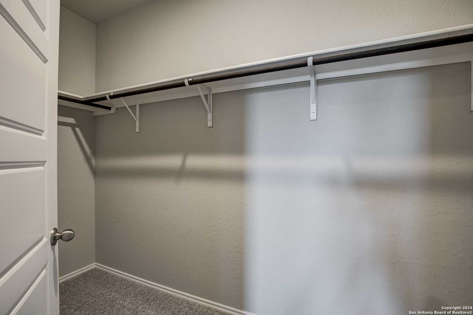 Spacious walk-in closet with white shelves and hanging rods in Davidson Homes The Daphne J, Seguin, Texas