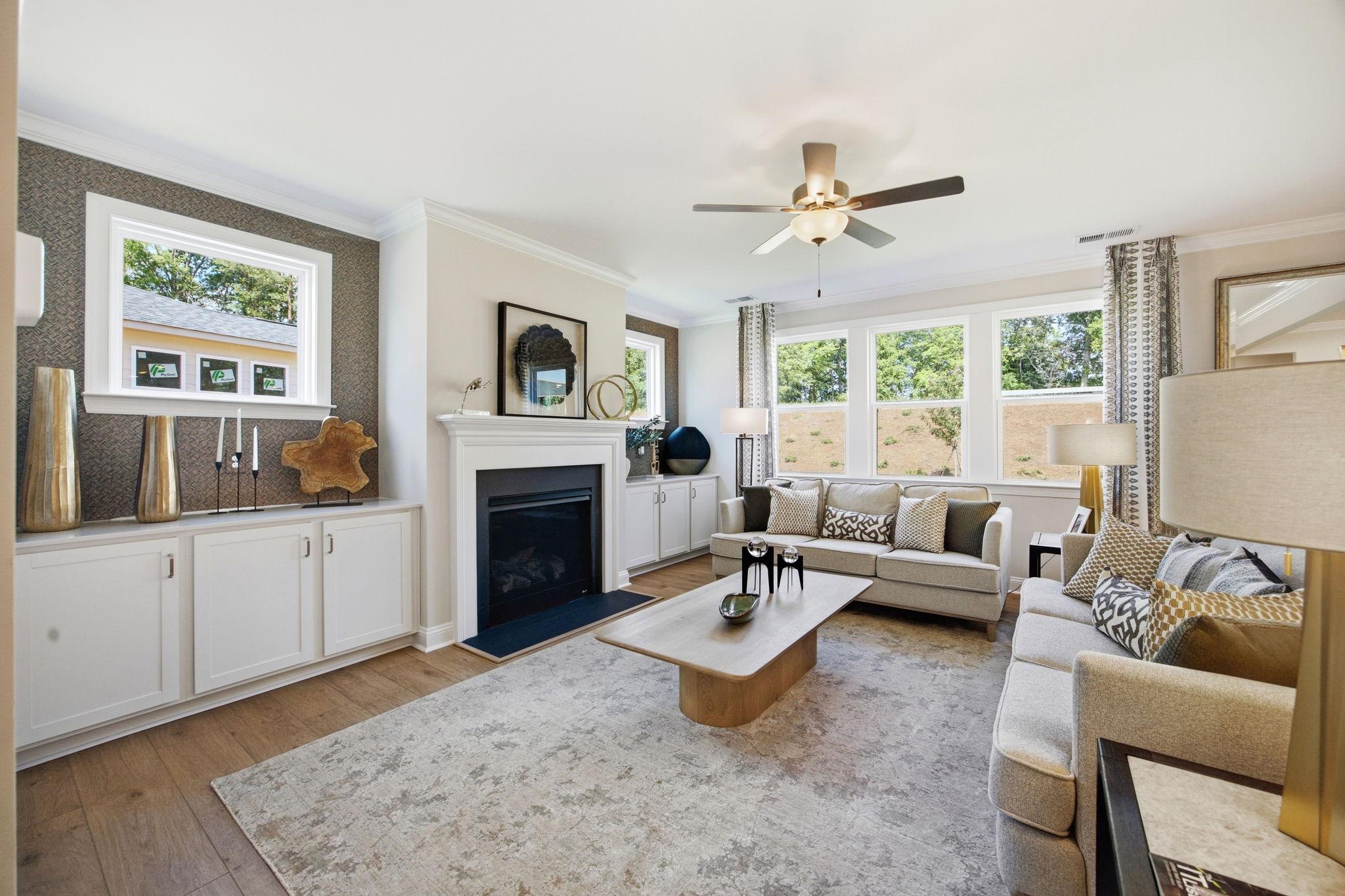 Cozy living room at Enclave at Belmont, Belmont NC with beige sectional sofa, gas fireplace, hardwood floors, and large windows