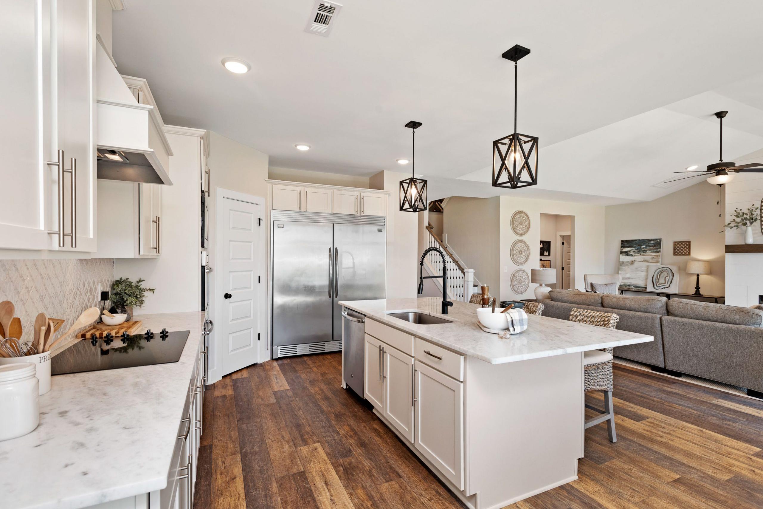 Open-concept kitchen and living room at Rivers Edge in Murfreesboro TN with white cabinets, marble island, hardwood floors, sectional sofa