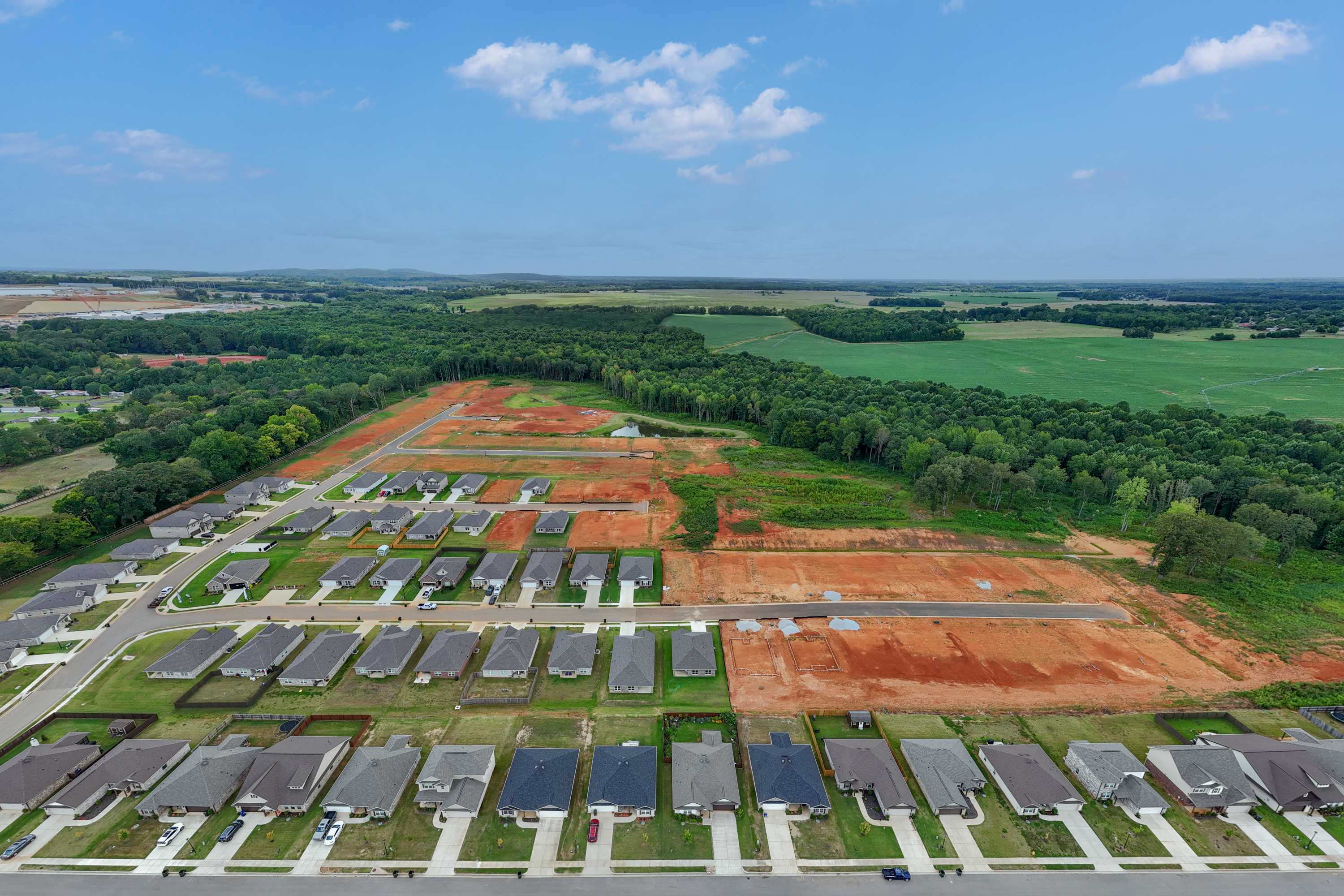 Aerial view of Wood Trail neighborhood in Toney Alabama with new Davidson Homes, construction sites, and surrounding green fields
