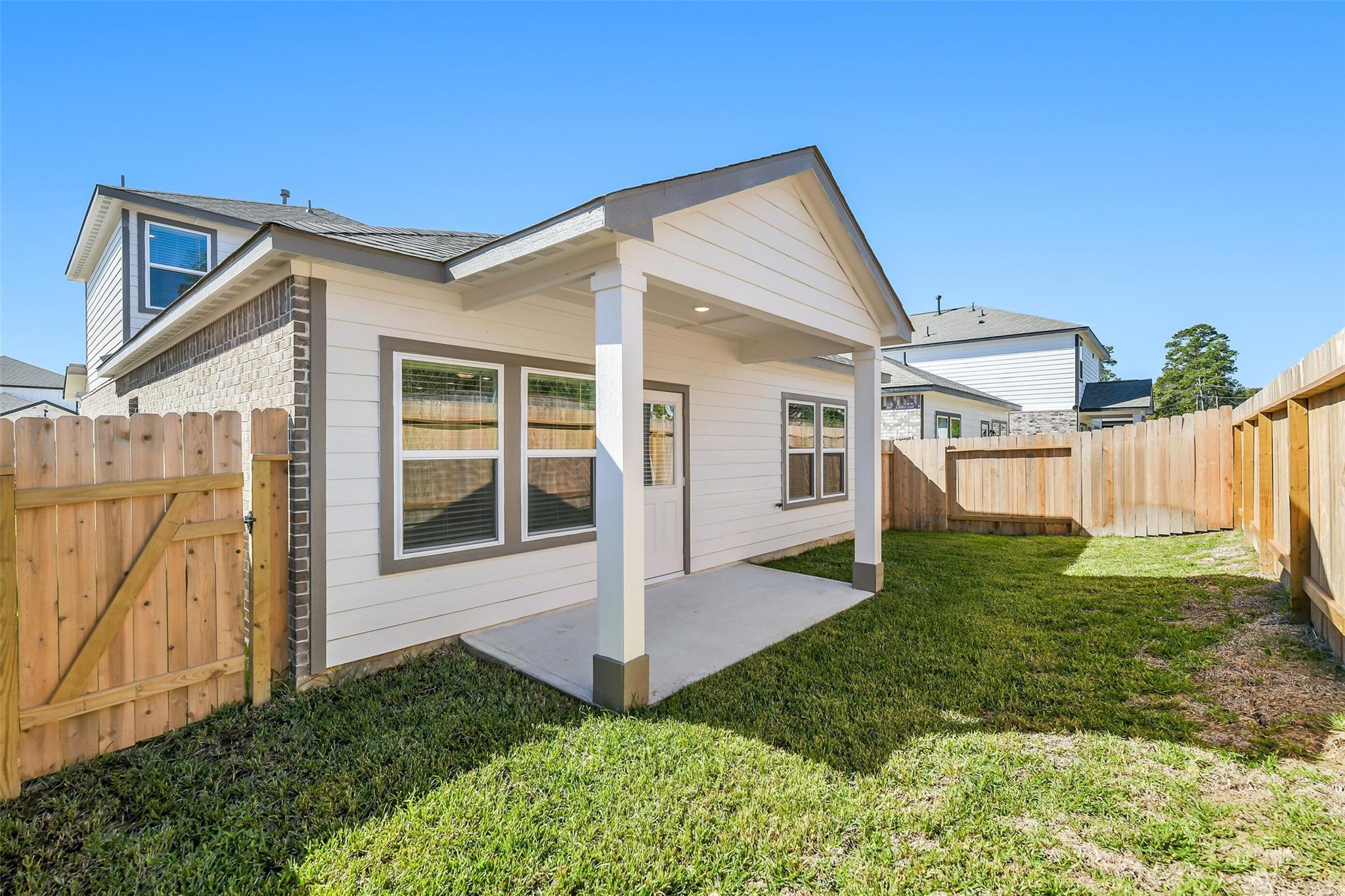 Covered back patio with columns and fenced green backyard of Davidson Homes The Blanco E in Lakes at Black Oak, Magnolia, Texas