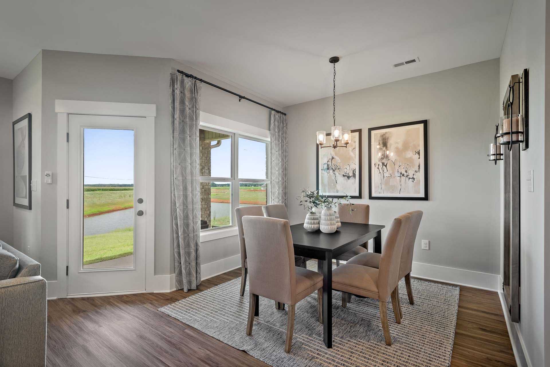 Spacious dining room at Heritage Lakes in New Market Alabama with lake view windows, wooden table, chandelier, and gray walls