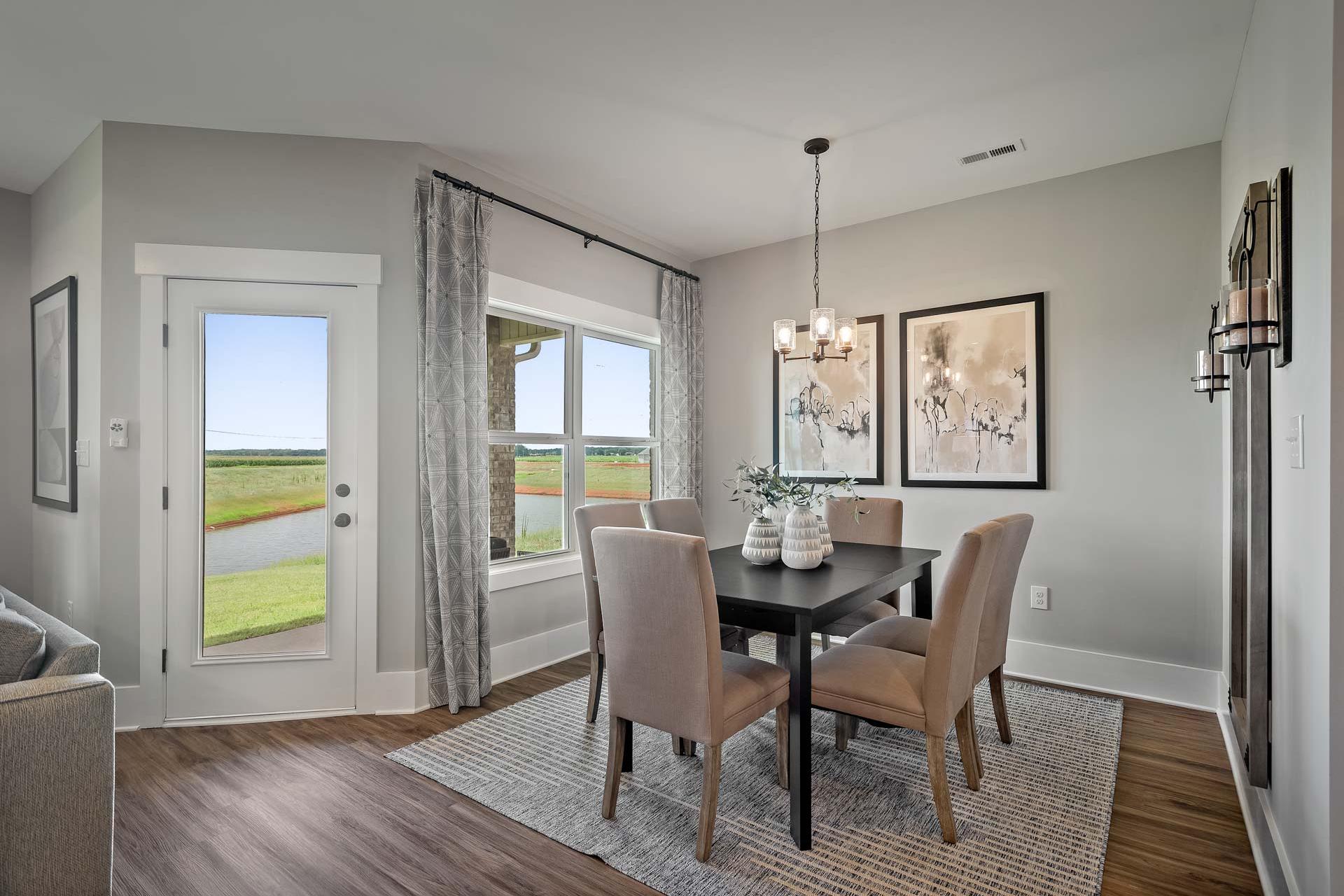 Spacious dining room at Heritage Lakes in New Market Alabama with lake view windows, wooden table, chandelier, and gray walls