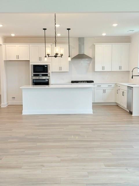 Modern white kitchen with island, stainless steel appliances, and wood-look flooring at The Hickory B in Wehunt Meadows.