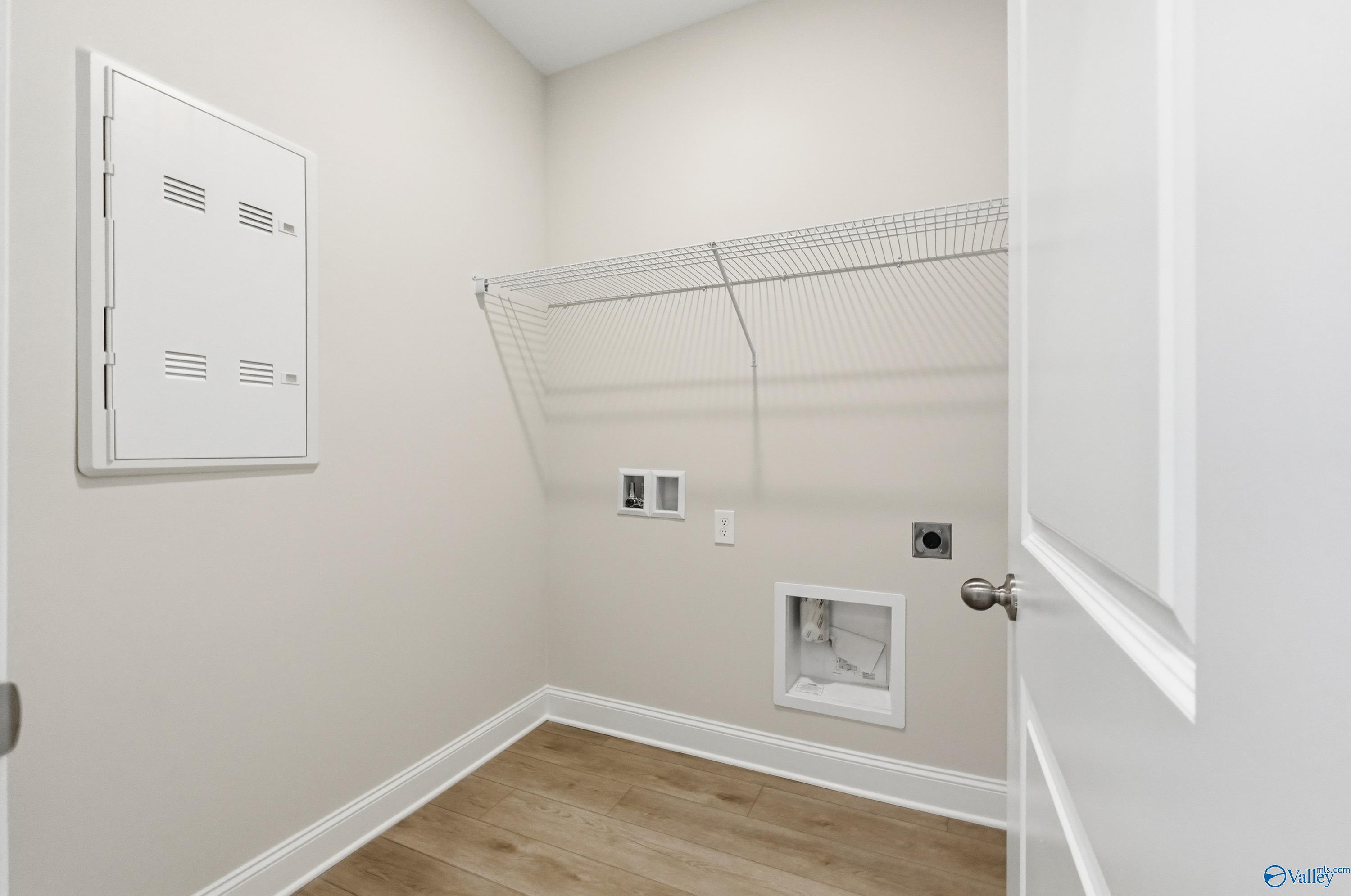 Functional laundry room with wire shelving, washer dryer hookups and neutral beige walls in Davidson Homes The Franklin, Meridianville, Alabama