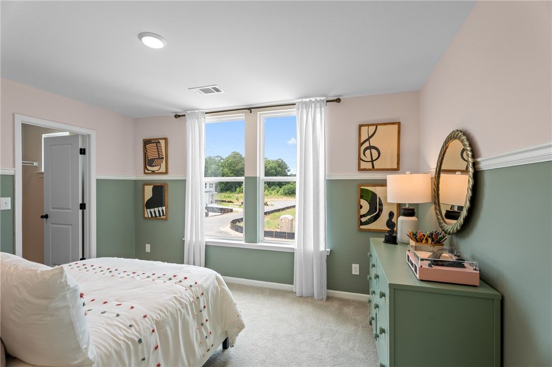 Bright bedroom with two-tone sage walls, large windows, and green dresser in Davidson Homes The Stella B, Opelika, Alabama