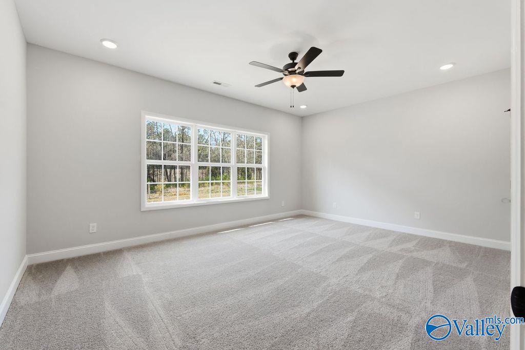 Bright bedroom with large windows, ceiling fan, gray walls, and carpet in Davidson Homes Montgomery B, Hartselle AL