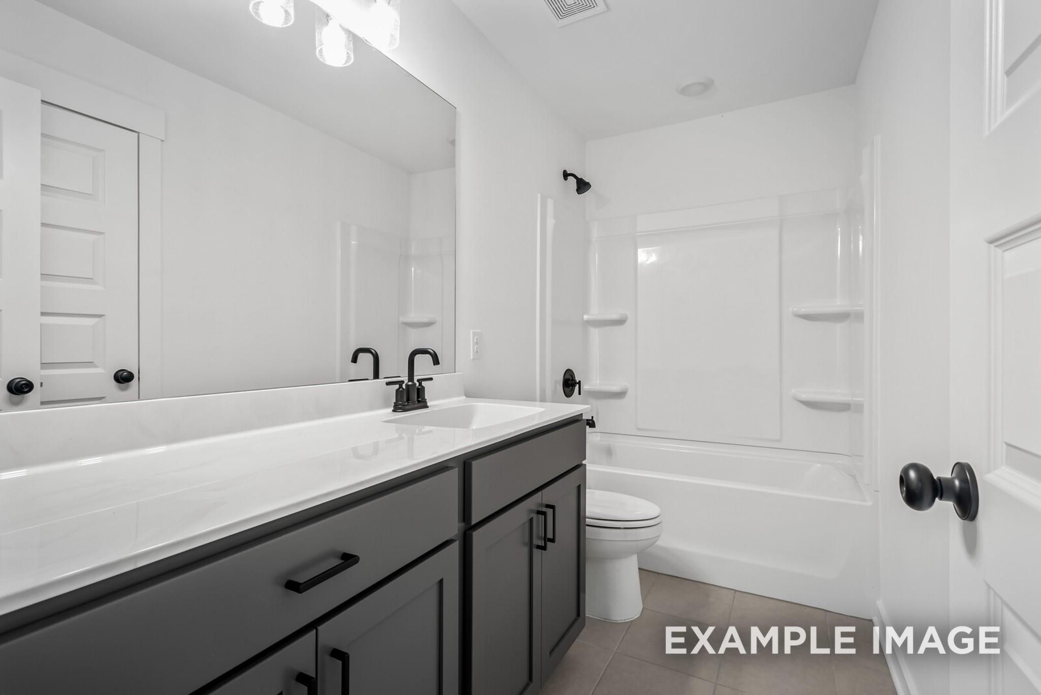 Modern secondary bathroom featuring white tub-shower combo, black shaker vanity, and quartz countertop in Davidson Homes The Ridgeport C, Gallatin, TN