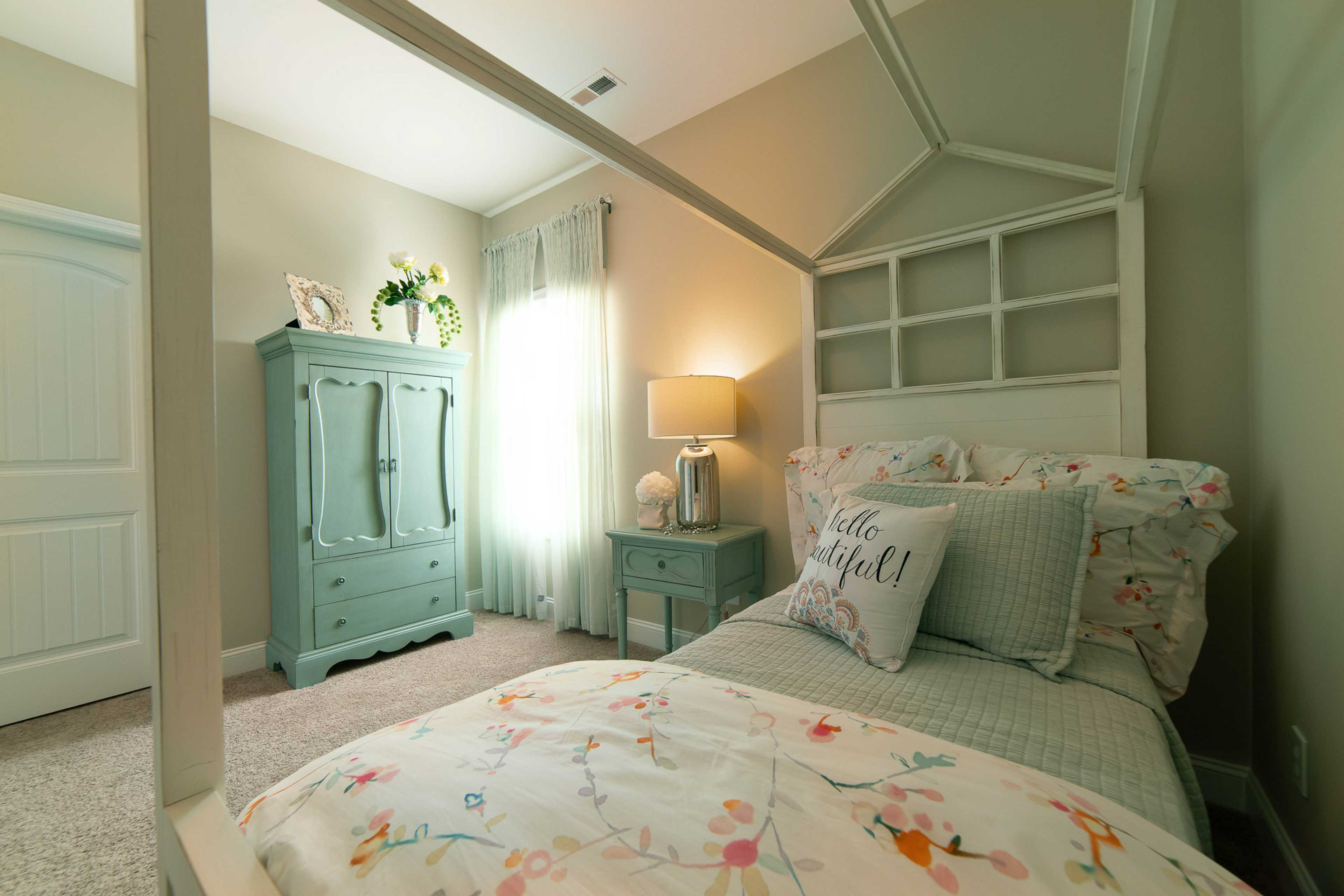 Charming girl's canopy bedroom at The Dairy at Oak Grove in South Huntsville AL with floral bedding, turquoise dresser, and lamp