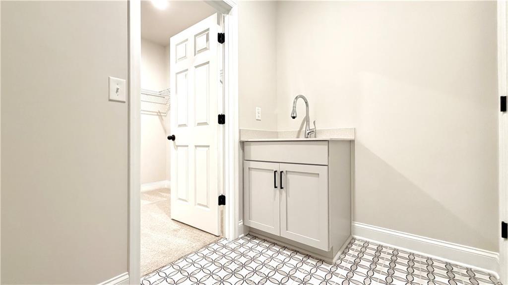Laundry room with utility sink and storage closet in The Ash C floor plan at Wehunt Meadows, Hoschton, Georgia.