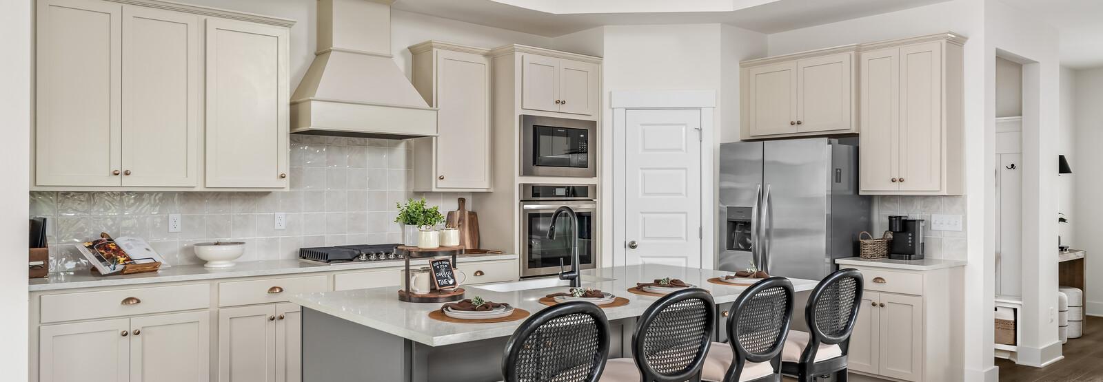 Spacious modern kitchen at Woods Crossing in Gallatin TN with white shaker cabinets, stainless appliances, and gray island bar seating