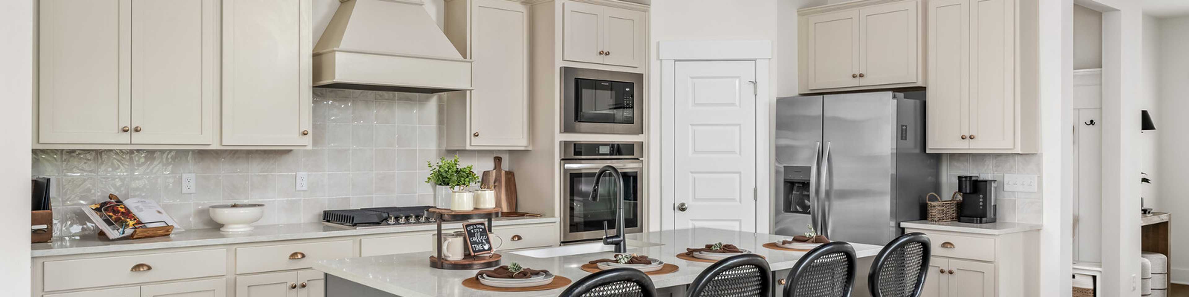 Spacious modern kitchen at Woods Crossing in Gallatin TN with white shaker cabinets, stainless appliances, and gray island bar seating