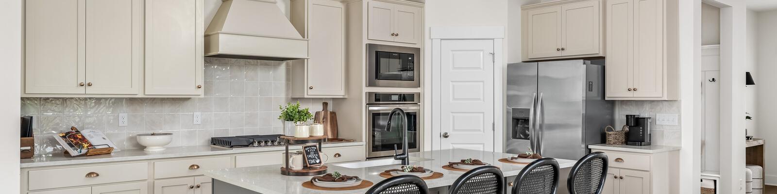 Spacious modern kitchen at Woods Crossing in Gallatin TN with white shaker cabinets, stainless appliances, and gray island bar seating