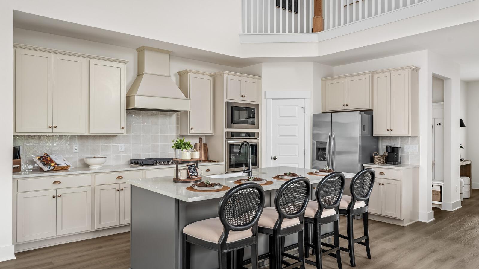 Spacious modern kitchen at Woods Crossing in Gallatin TN with white shaker cabinets, stainless appliances, and gray island bar seating