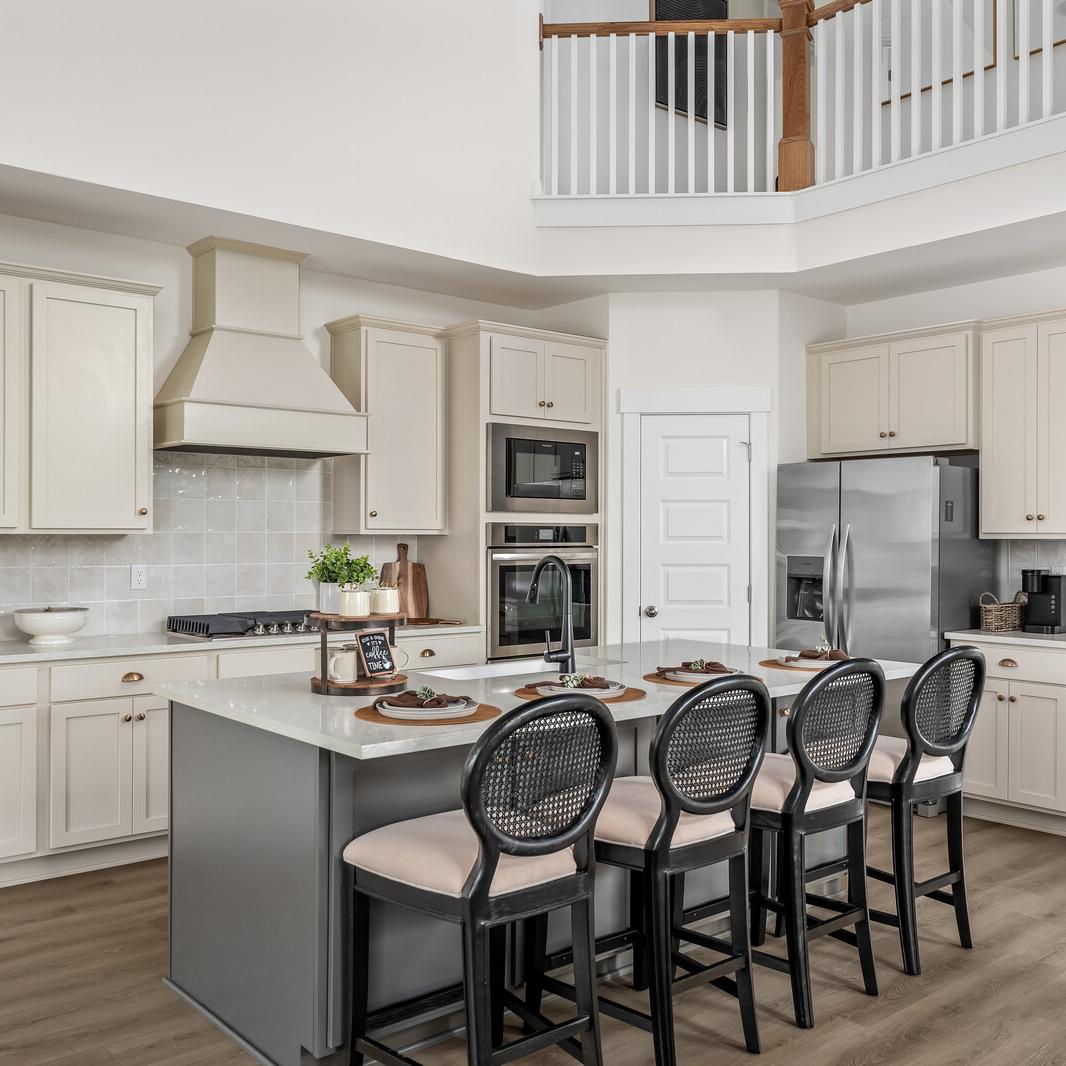 Spacious modern kitchen at Woods Crossing in Gallatin TN with white shaker cabinets, stainless appliances, and gray island bar seating