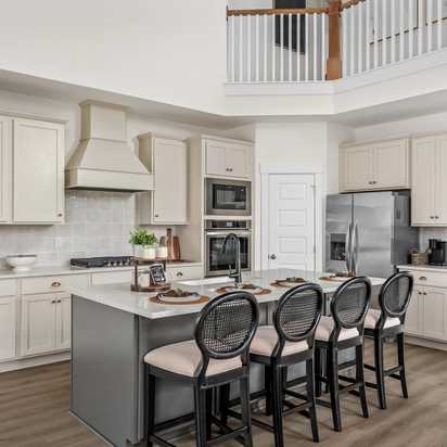 Spacious modern kitchen at Woods Crossing in Gallatin TN with white shaker cabinets, stainless appliances, and gray island bar seating