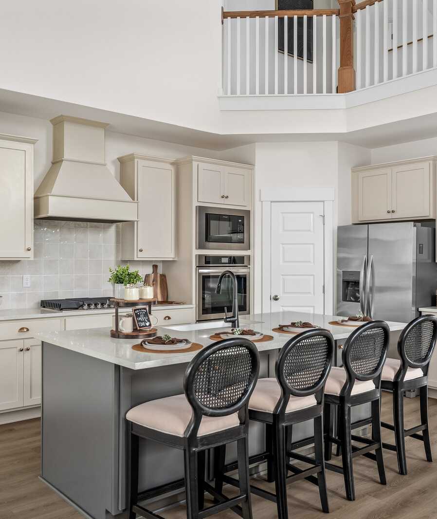 Spacious modern kitchen at Woods Crossing in Gallatin TN with white shaker cabinets, stainless appliances, and gray island bar seating