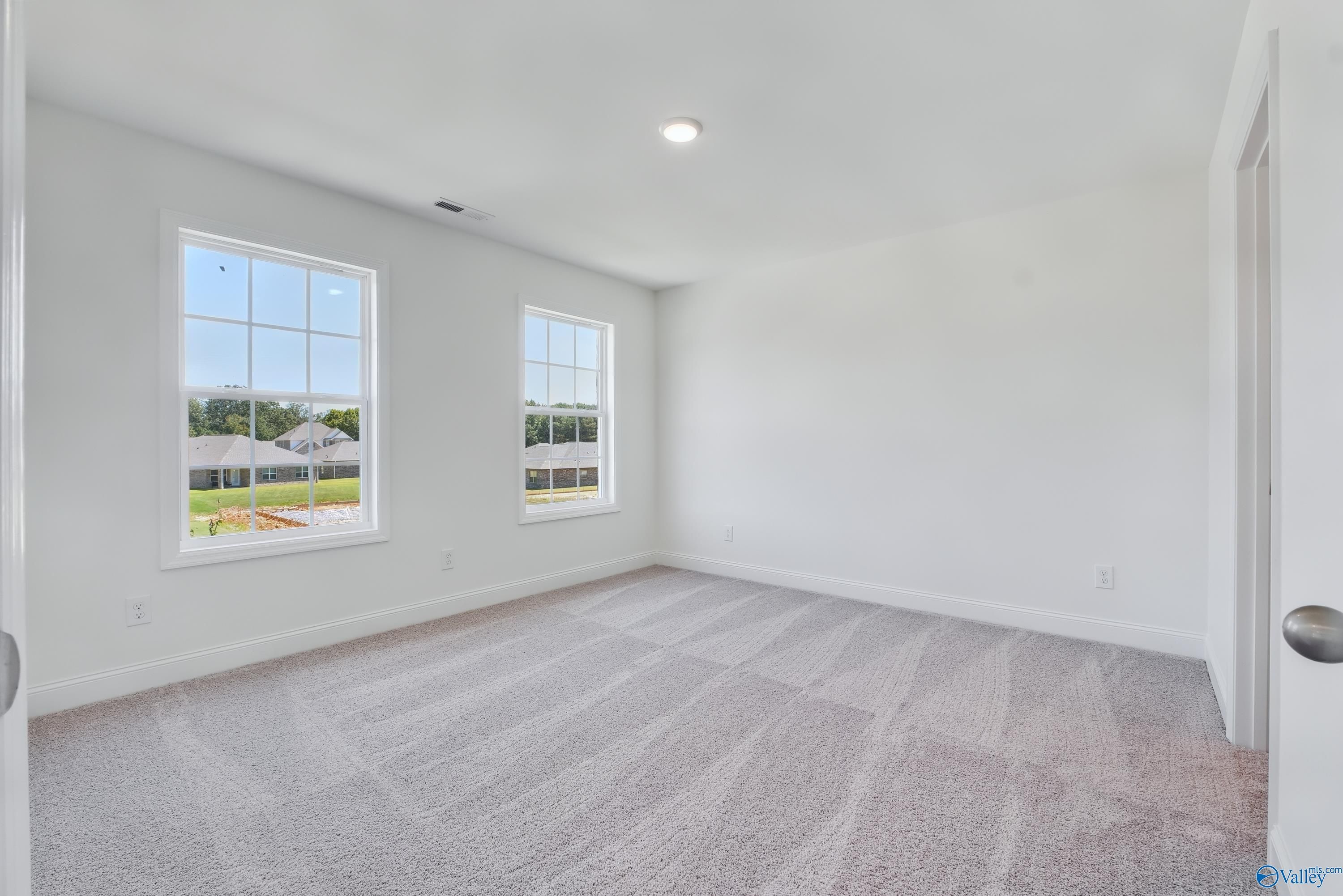Spacious secondary bedroom with large windows overlooking lush greenery, neutral walls, and carpeted floors in The Shelby A, Arab, Alabama