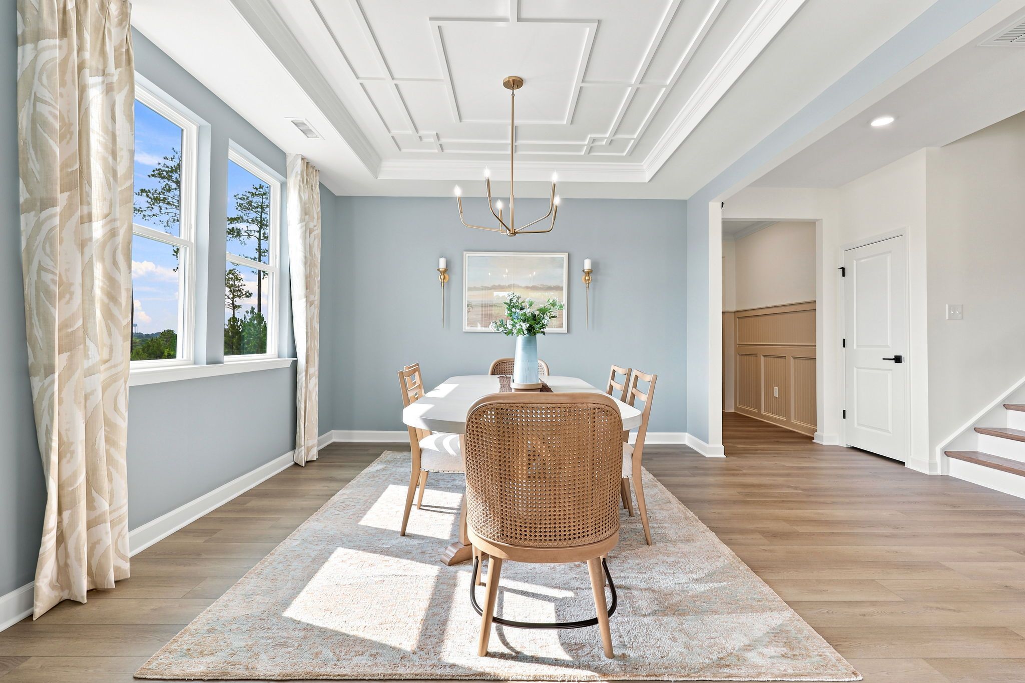 Elegant dining room at Montrose in Aberdeen, NC by Davidson Homes featuring a coffered ceiling and cane-back chairs.