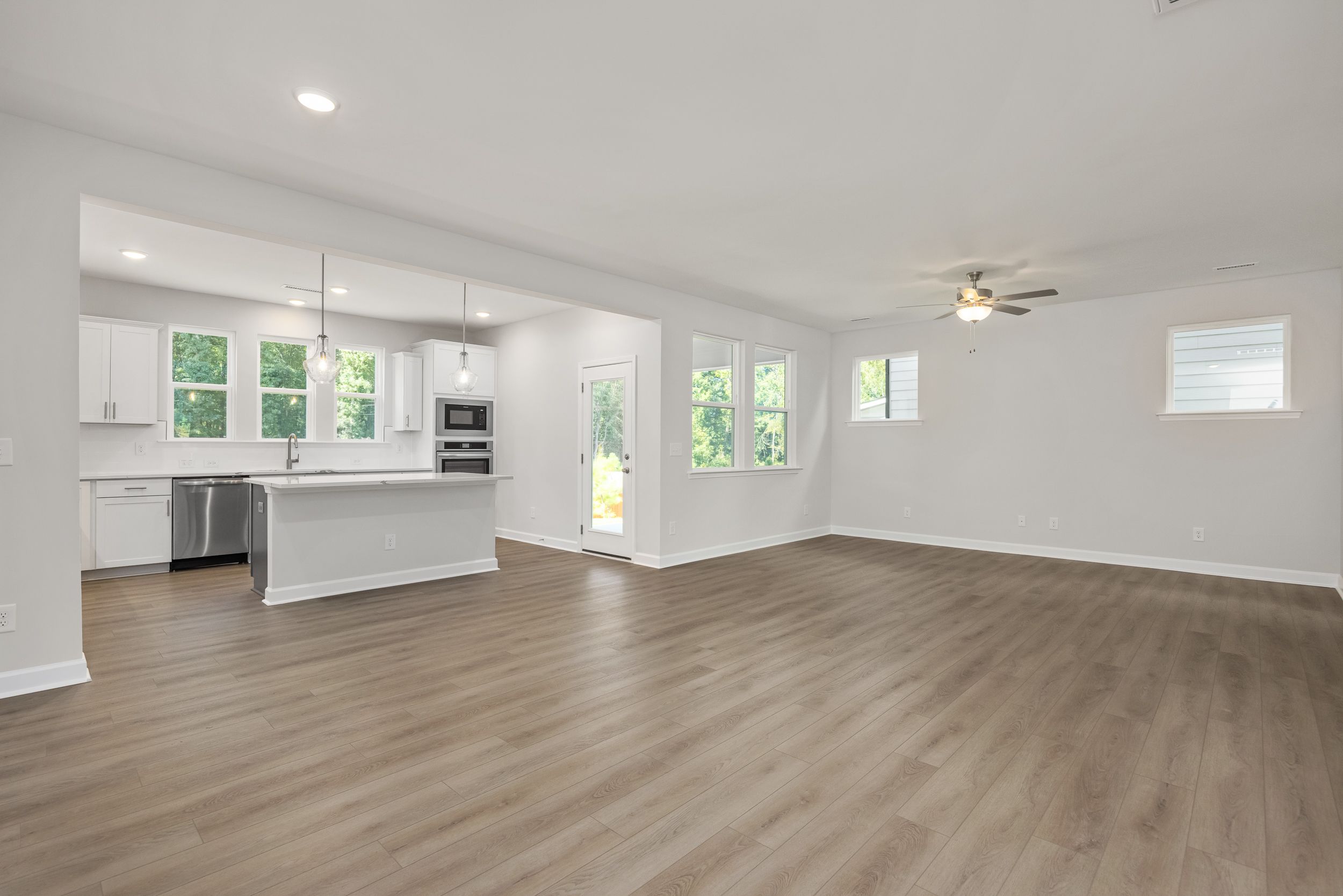 Spacious open-concept kitchen in The Aspen C with white cabinets, large island, stainless appliances, and hardwood floors