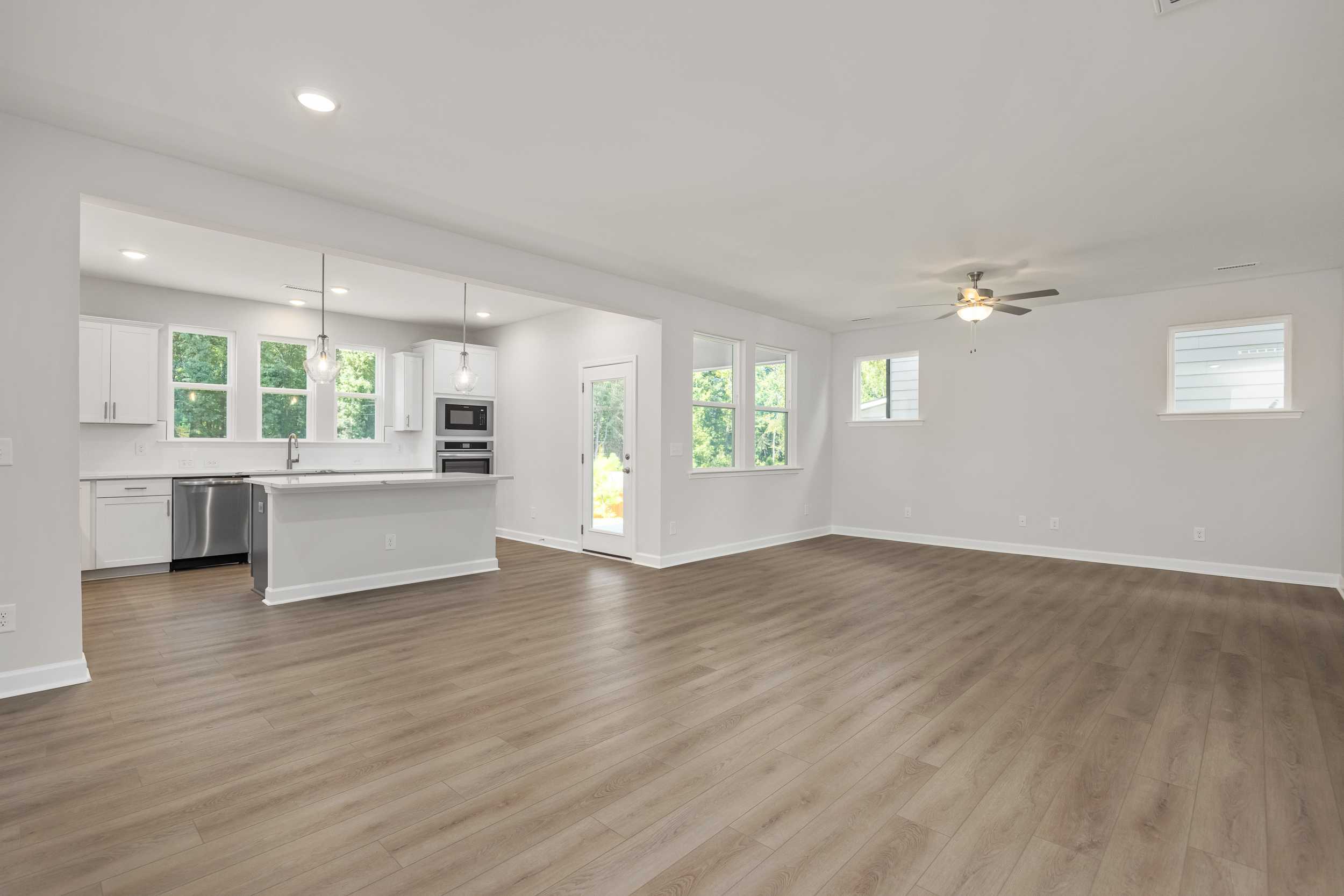 Spacious open-concept kitchen in The Aspen C with white cabinets, large island, stainless appliances, and hardwood floors