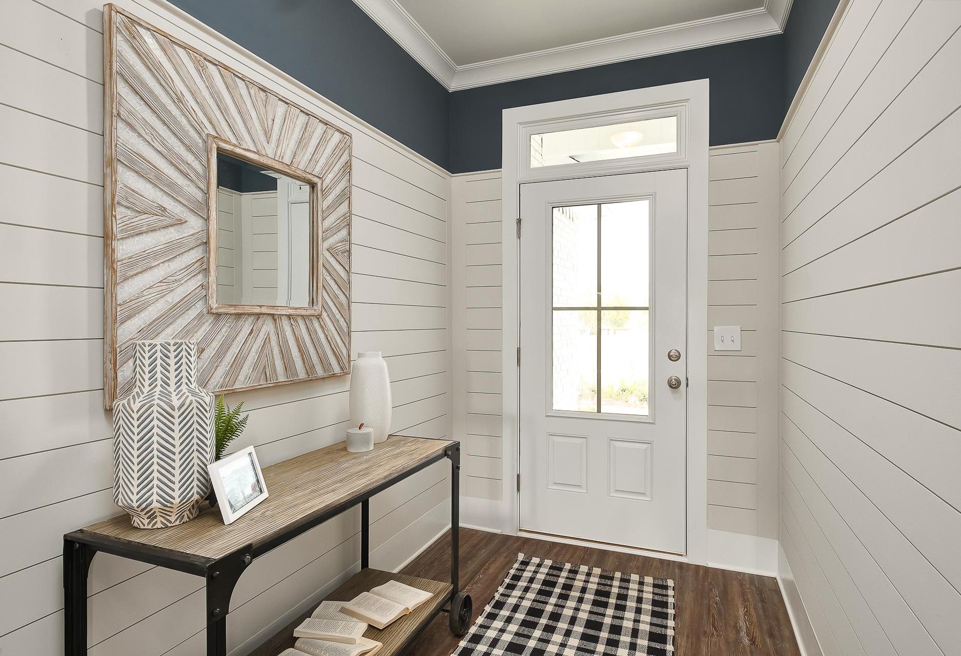 Spacious Everett home entryway with white shiplap walls, navy trim ceiling, starburst mirror, wooden console table, and glass door