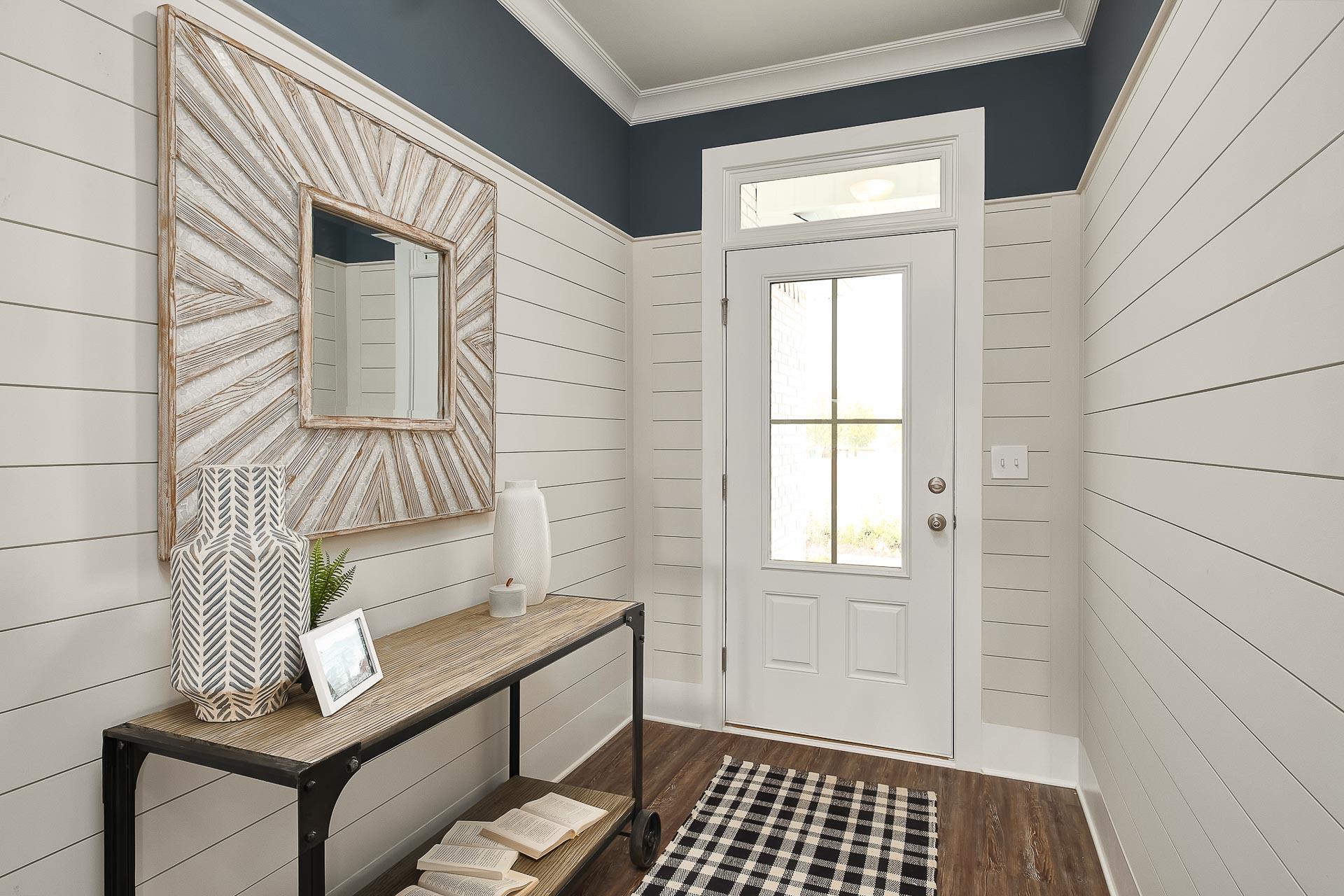 Spacious Everett home entryway with white shiplap walls, navy trim ceiling, starburst mirror, wooden console table, and glass door