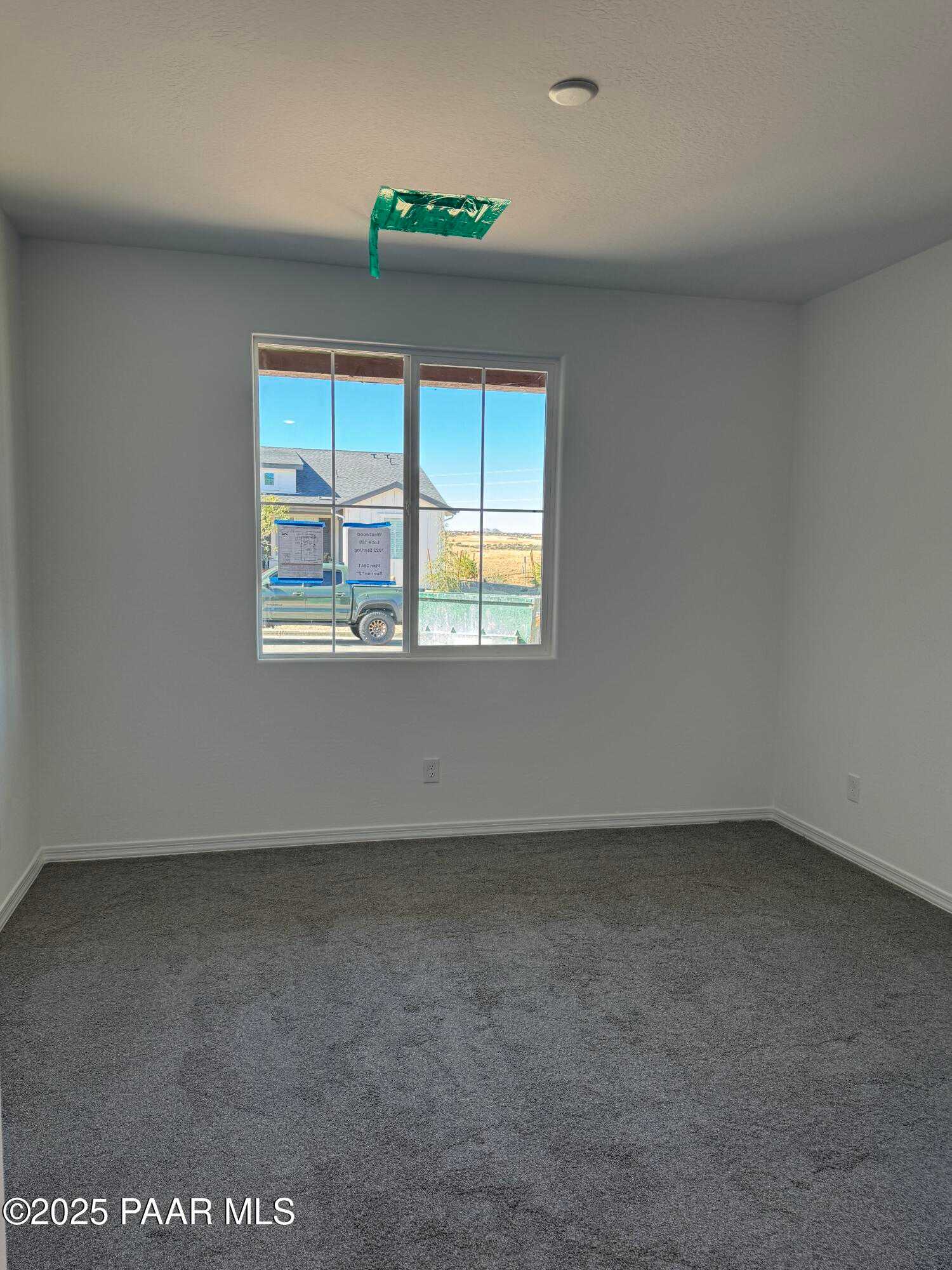 Spacious empty bedroom with large window, white walls, gray carpet in Davidson Homes Sunrise II A, Prescott AZ