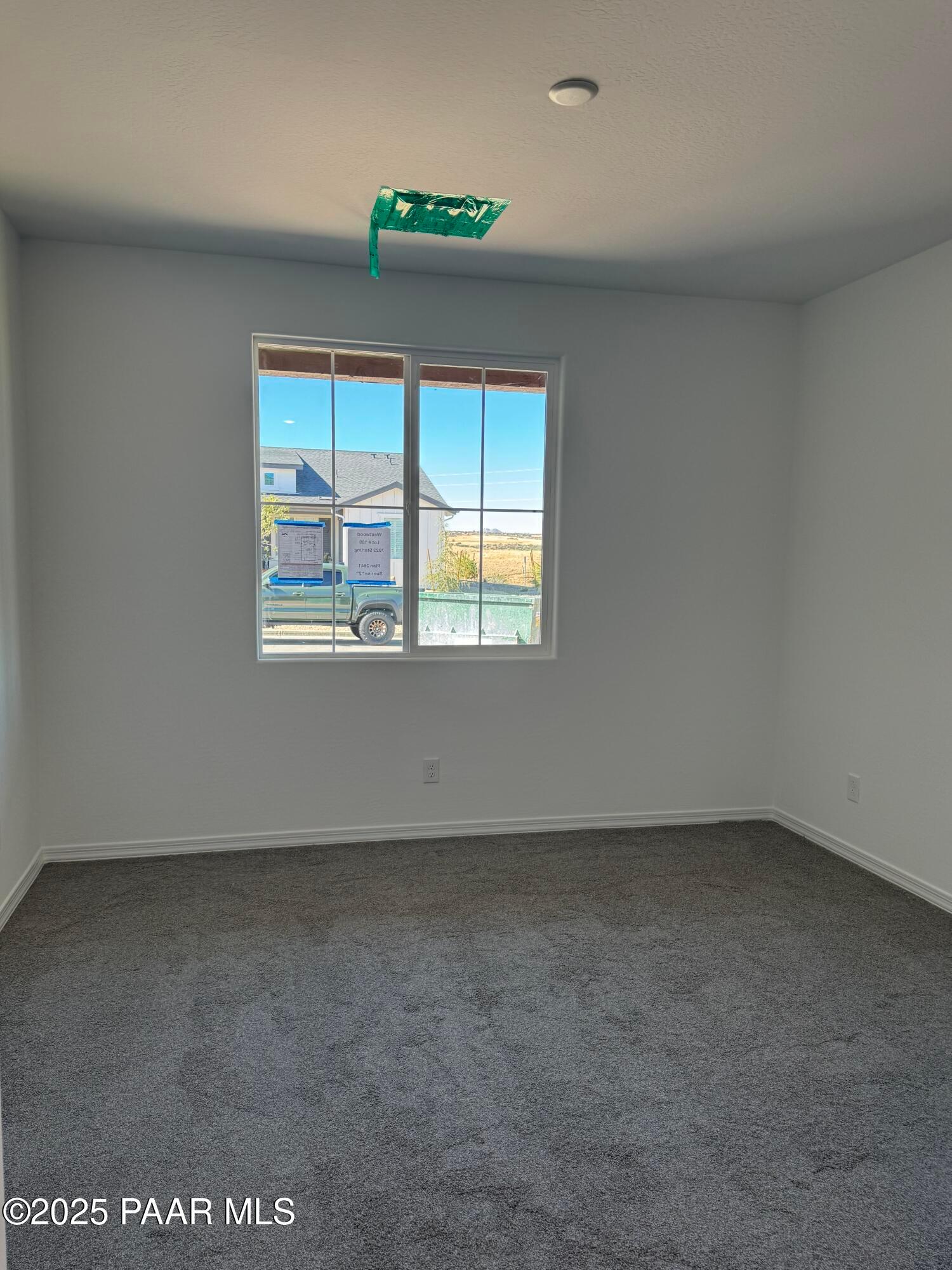 Spacious empty bedroom with large window, white walls, gray carpet in Davidson Homes Sunrise II A, Prescott AZ