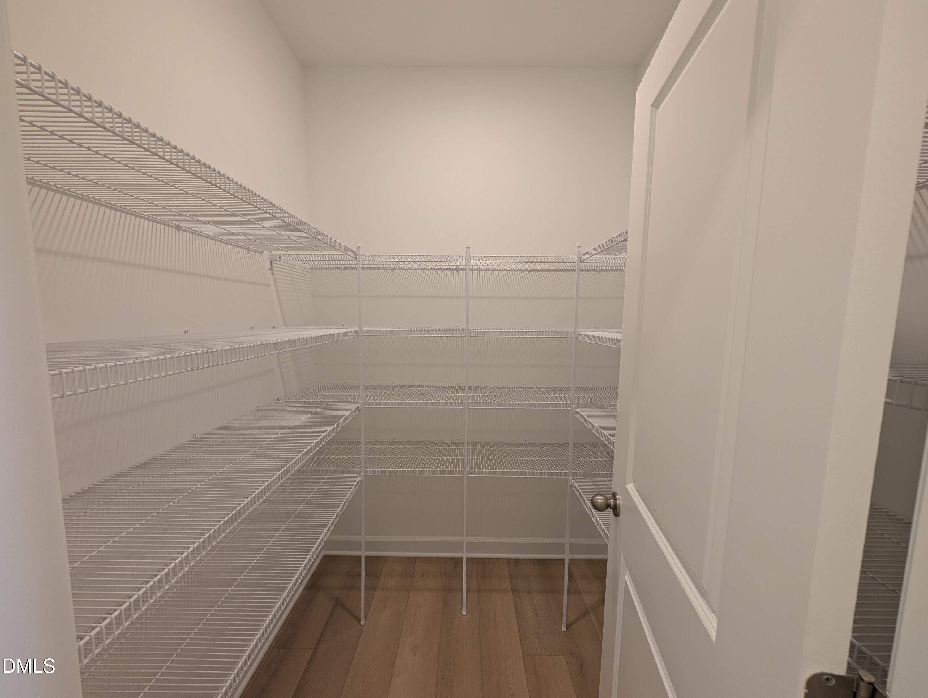 Walk-in closet with white wire shelving and wood-look flooring in Davidson Homes Magnolia A, Wendell Ridge, North Carolina