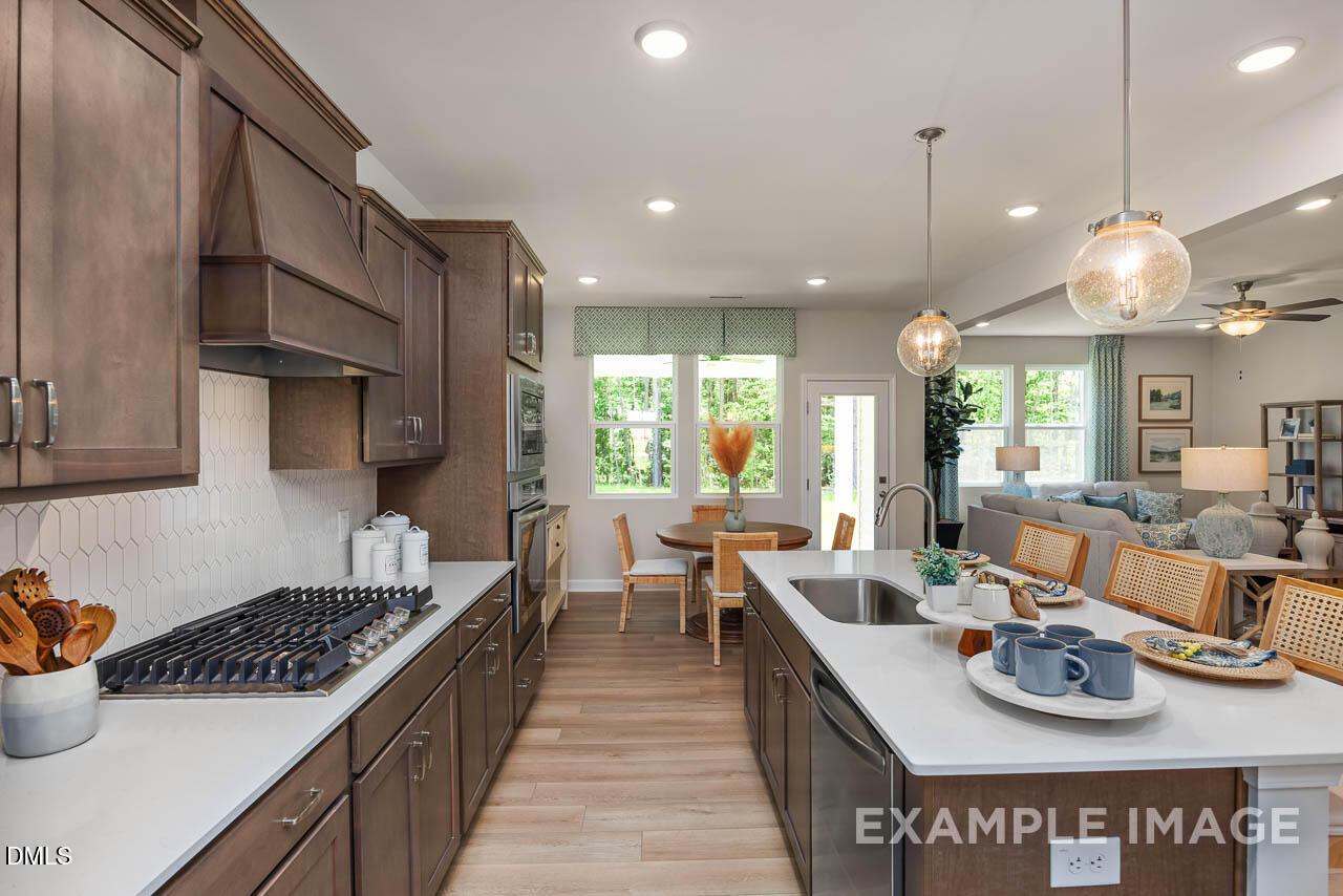 Open-concept kitchen with espresso cabinets, white quartz counters, gas range, and adjacent dining area in Davidson Homes Willow B, Wake Forest NC