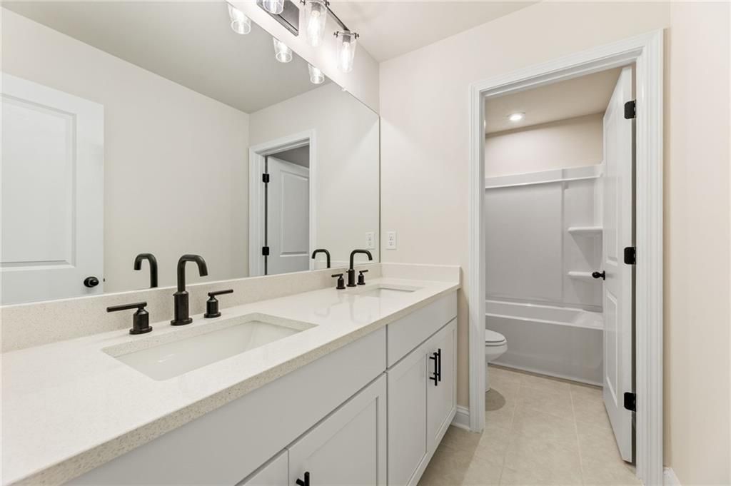 Modern master bathroom with double white quartz vanity, black faucets, and glass shower in Davidson Homes Hickory E, Buford, GA