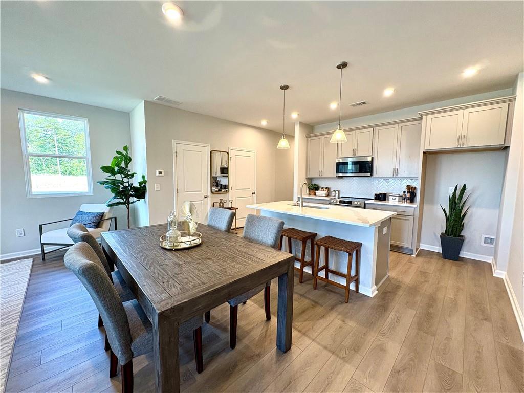 Open-concept dining with rustic wood table and bar stools, white kitchen island, pendant lights in Davidson Homes The Monroe A, Emerson, GA