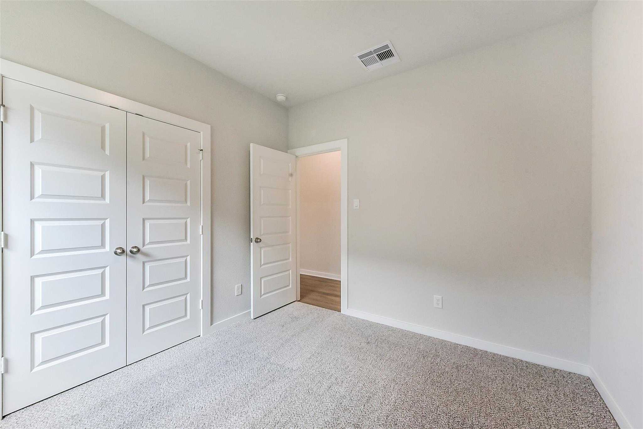 Spacious secondary bedroom featuring double closet doors and adjacent bathroom in Davidson Homes The Laguna C, Rosharon, Texas