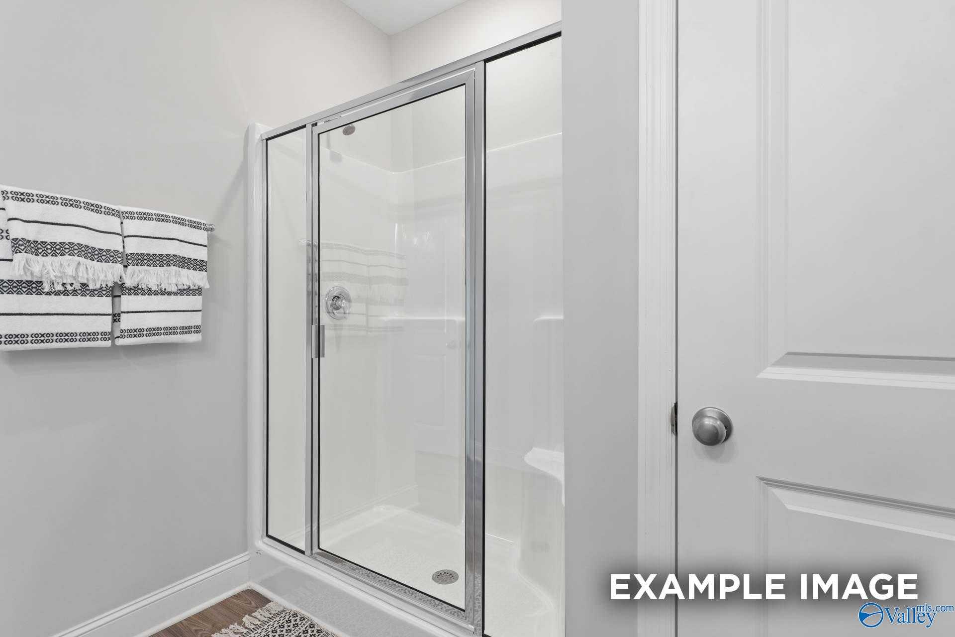 Modern master bathroom with frameless glass shower, white subway tiles, and towel rack in Davidson Homes The Franklin C, Meridianville, Alabama