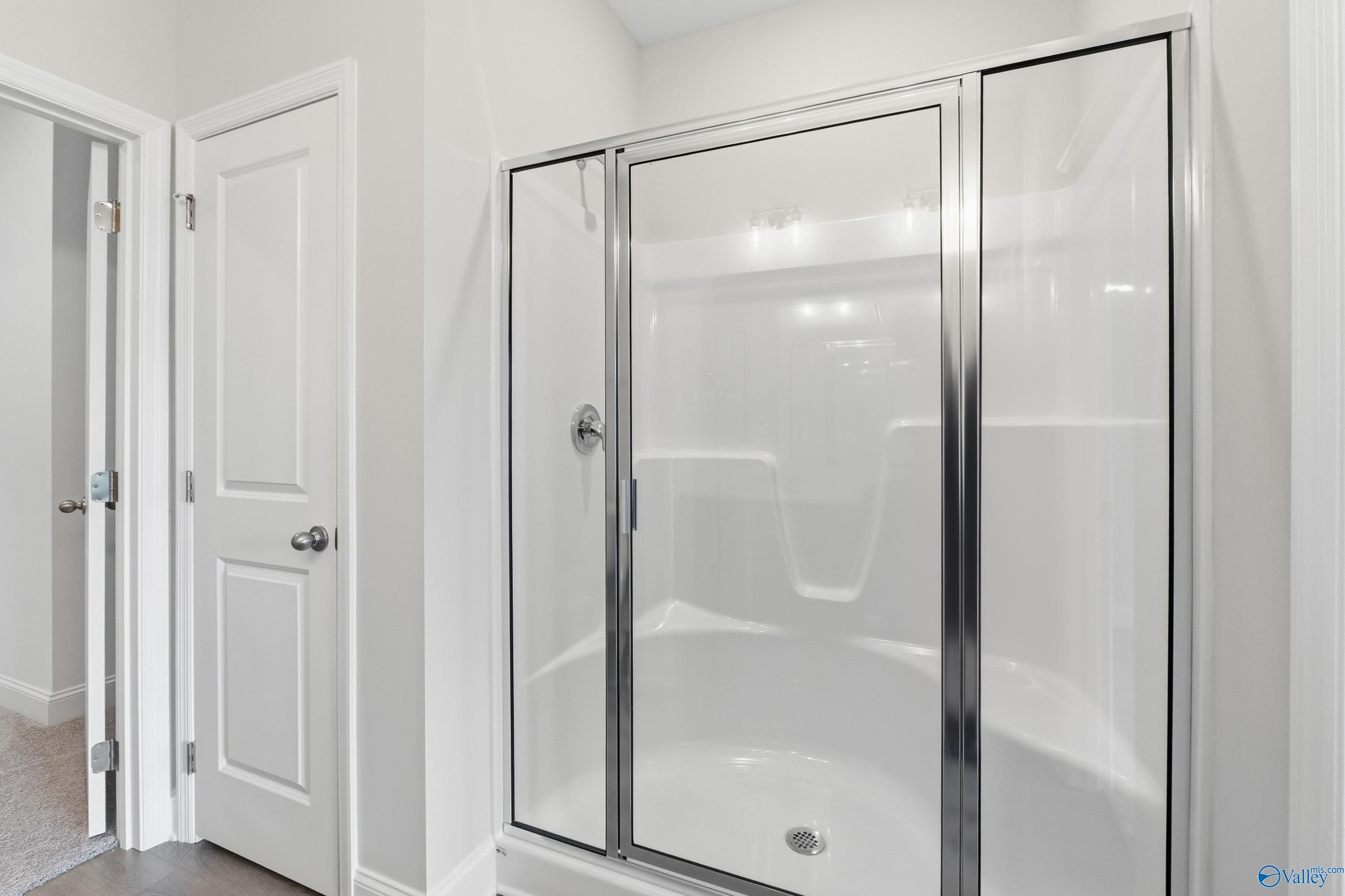 Modern master bathroom with glass shower enclosure and white tub in Davidson Homes The Asheville C, Huntsville, Alabama