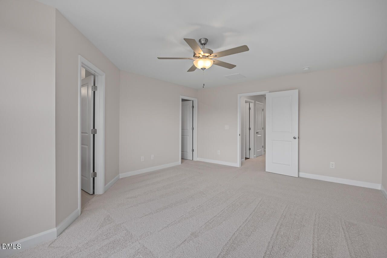 Spacious carpeted bedroom with ceiling fan in The Graham Interior floor plan by Davidson Homes in Springvale, Fuquay-Varina.