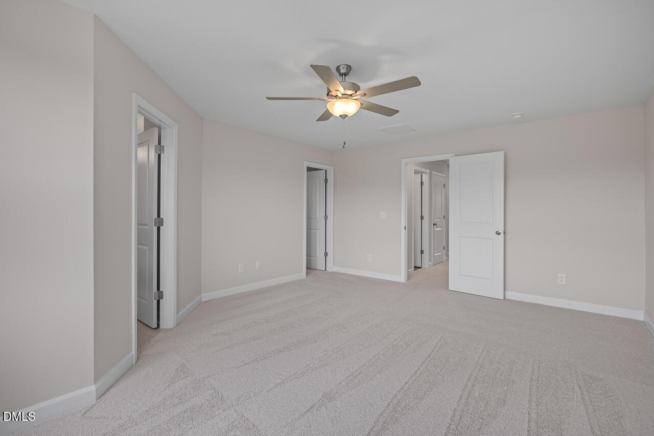 Spacious carpeted bedroom with ceiling fan in The Graham Interior floor plan by Davidson Homes in Springvale, Fuquay-Varina.