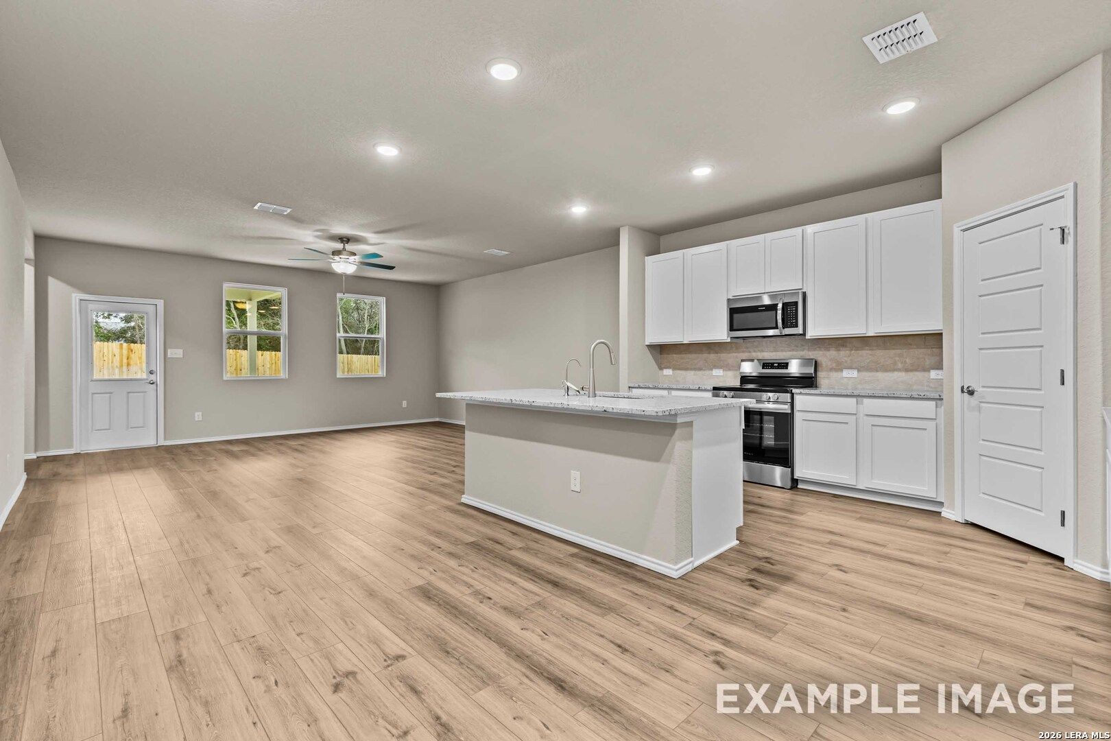 Open-concept kitchen with white cabinets and island in The Douglas F floor plan at Bricewood, San Antonio, Texas.