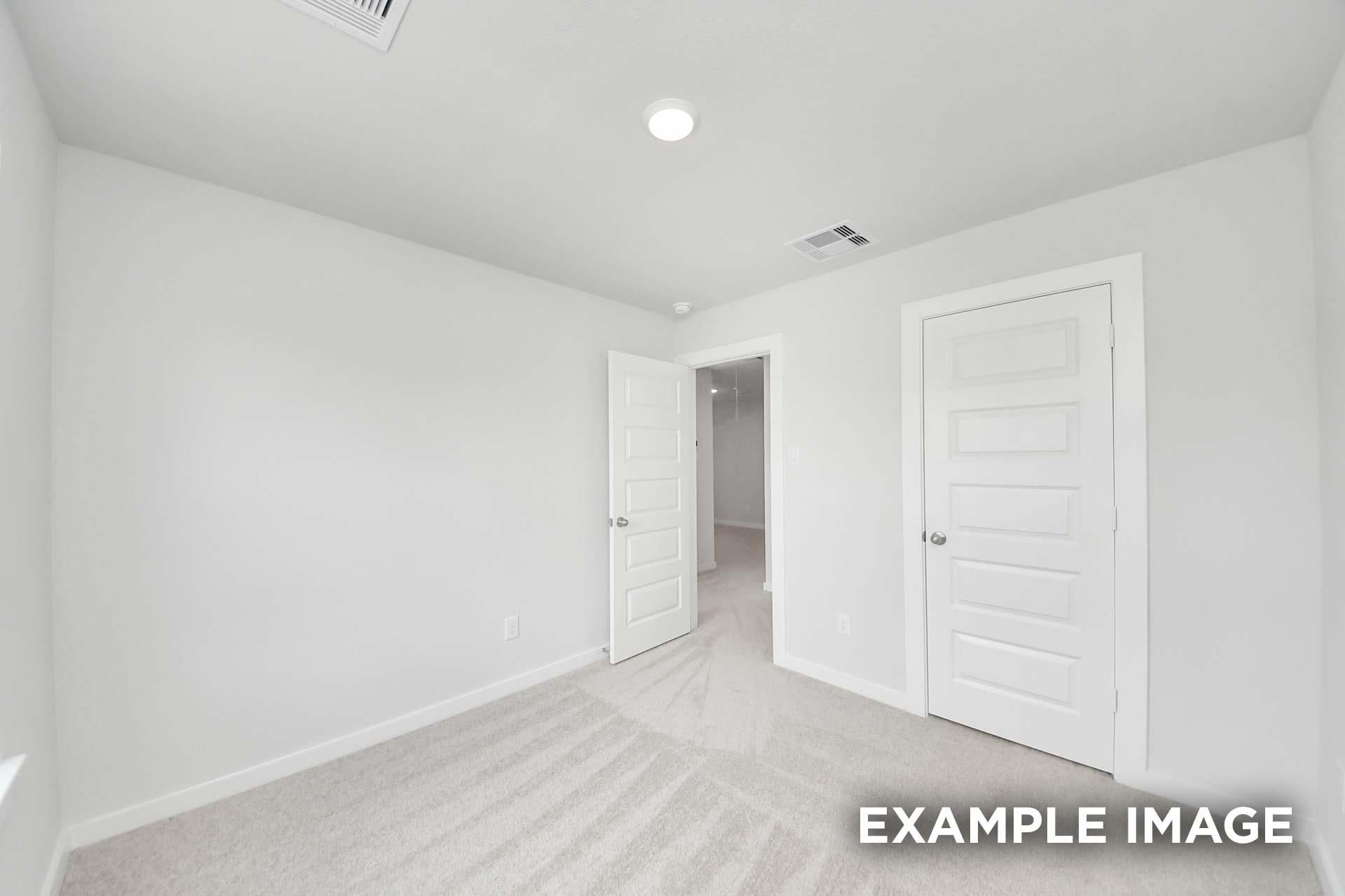 Bright carpeted bedroom with white doors and fresh neutral walls in The Blanco E floor plan by Davidson Homes, Magnolia, Texas