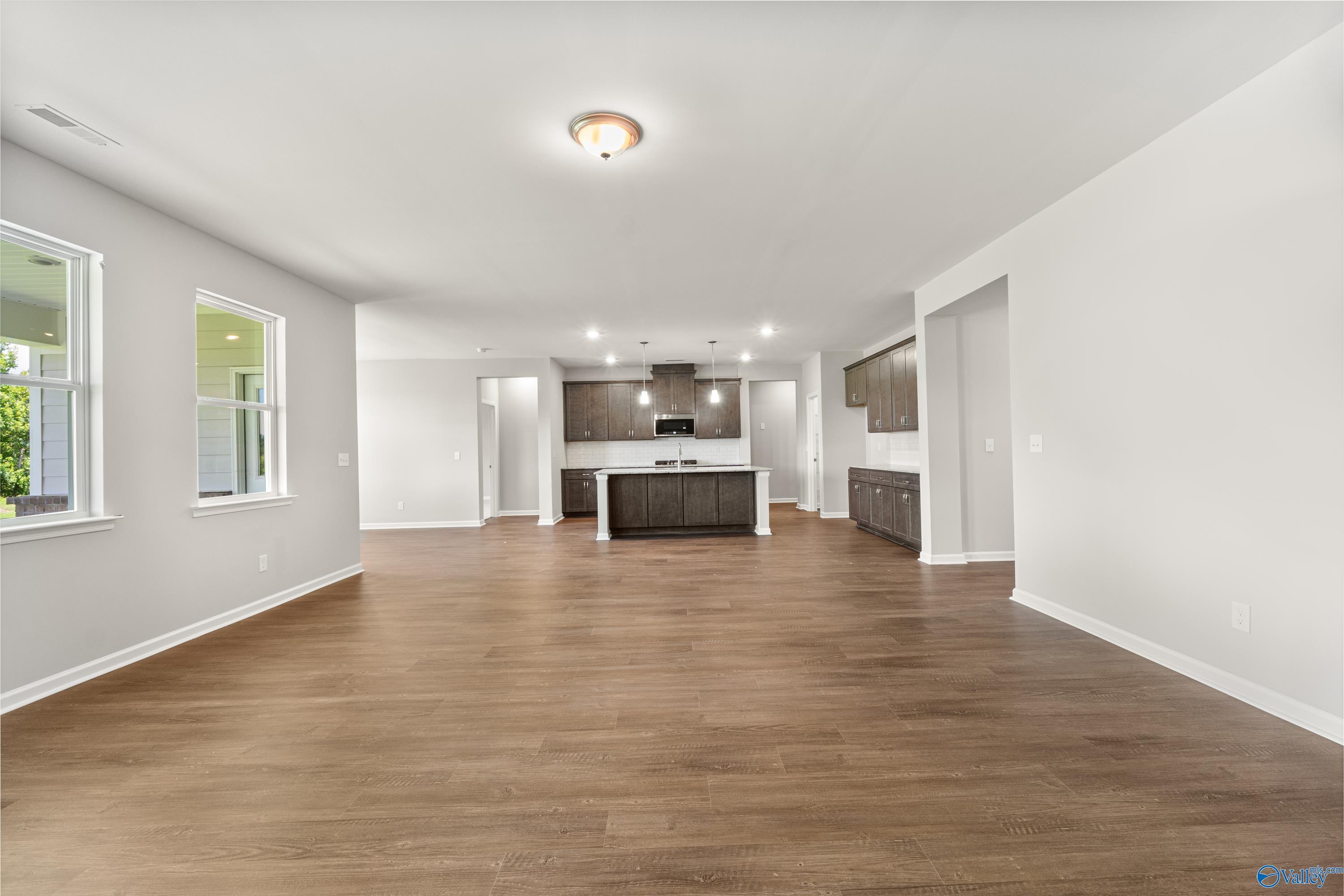 Open-concept kitchen with white shaker cabinets, large center island, and hardwood floors in Davidson Homes The Sanctuary, Huntsville AL