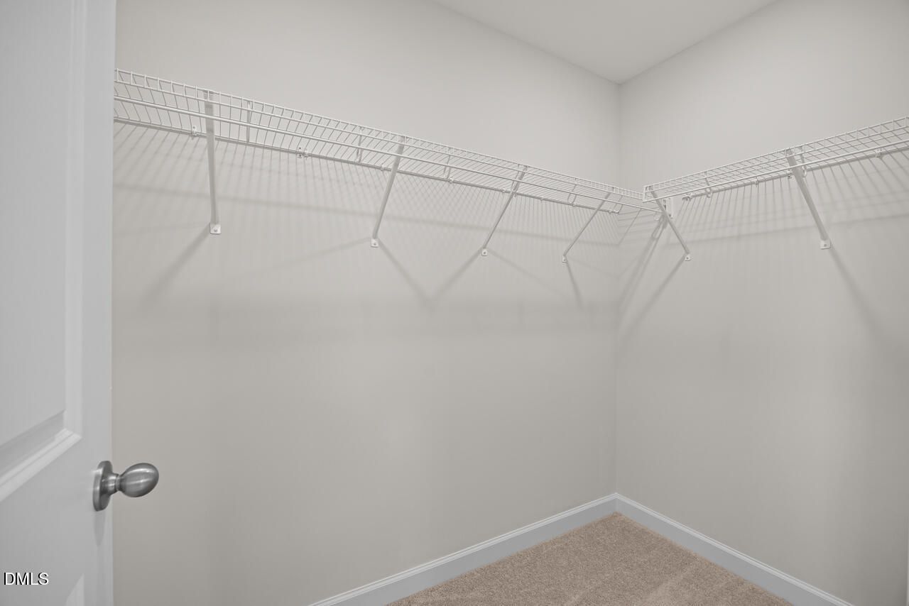 Spacious walk-in closet with wire shelving and carpet flooring in Davidson Homes' Mitchell plan, Forestville Yard Townhomes, Knightdale NC
