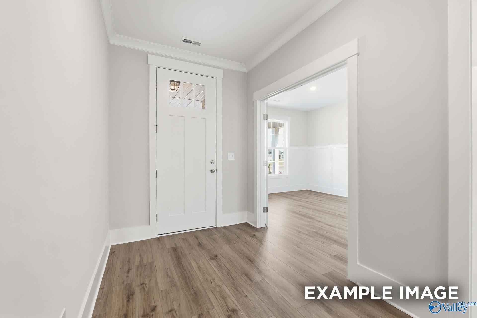 Bright entryway with wood-style flooring and white door in The Harrison floor plan by Davidson Homes, Meridianville, AL.