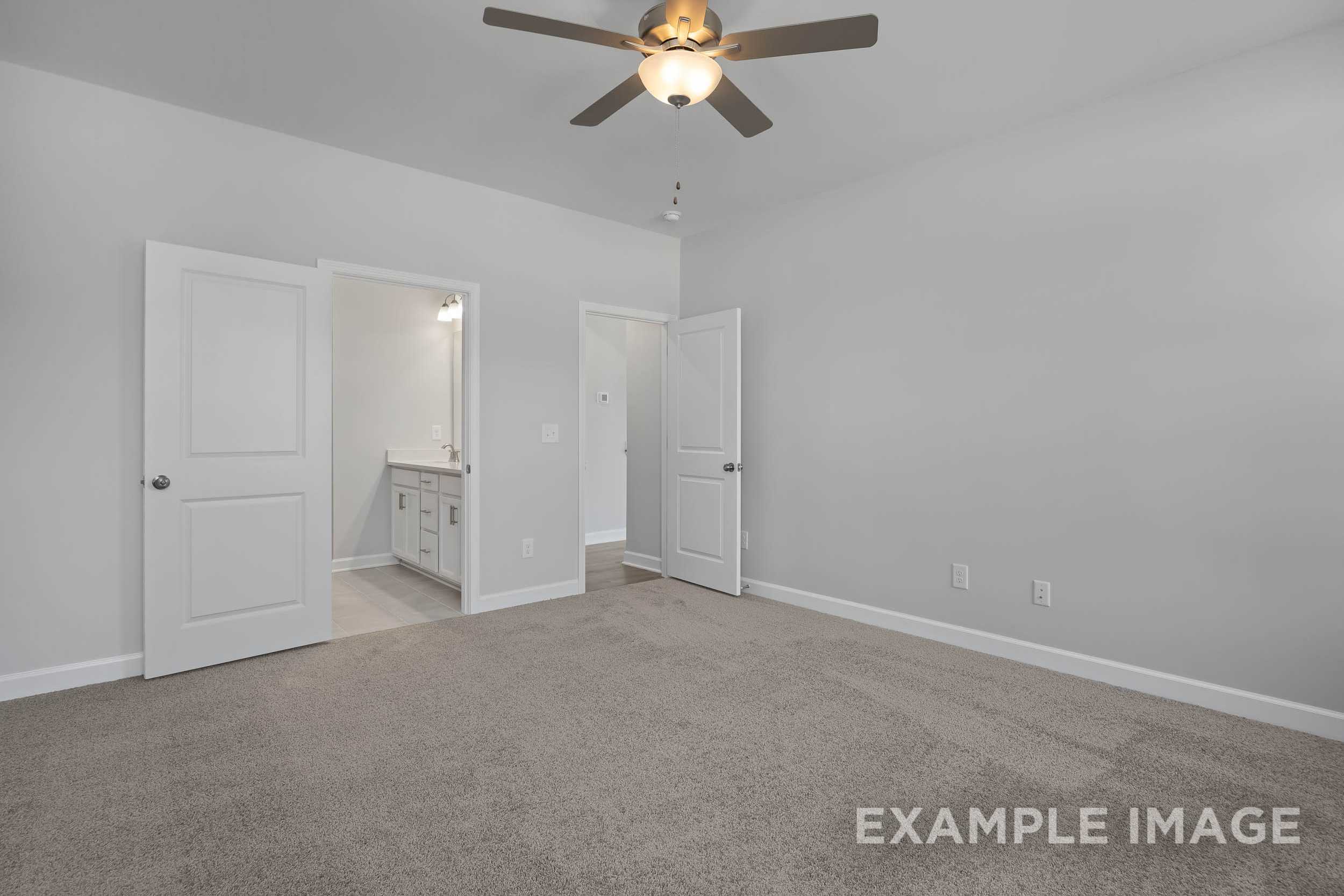 Spacious master bedroom in The Ash featuring open en-suite bathroom, ceiling fan, neutral gray walls, beige carpet
