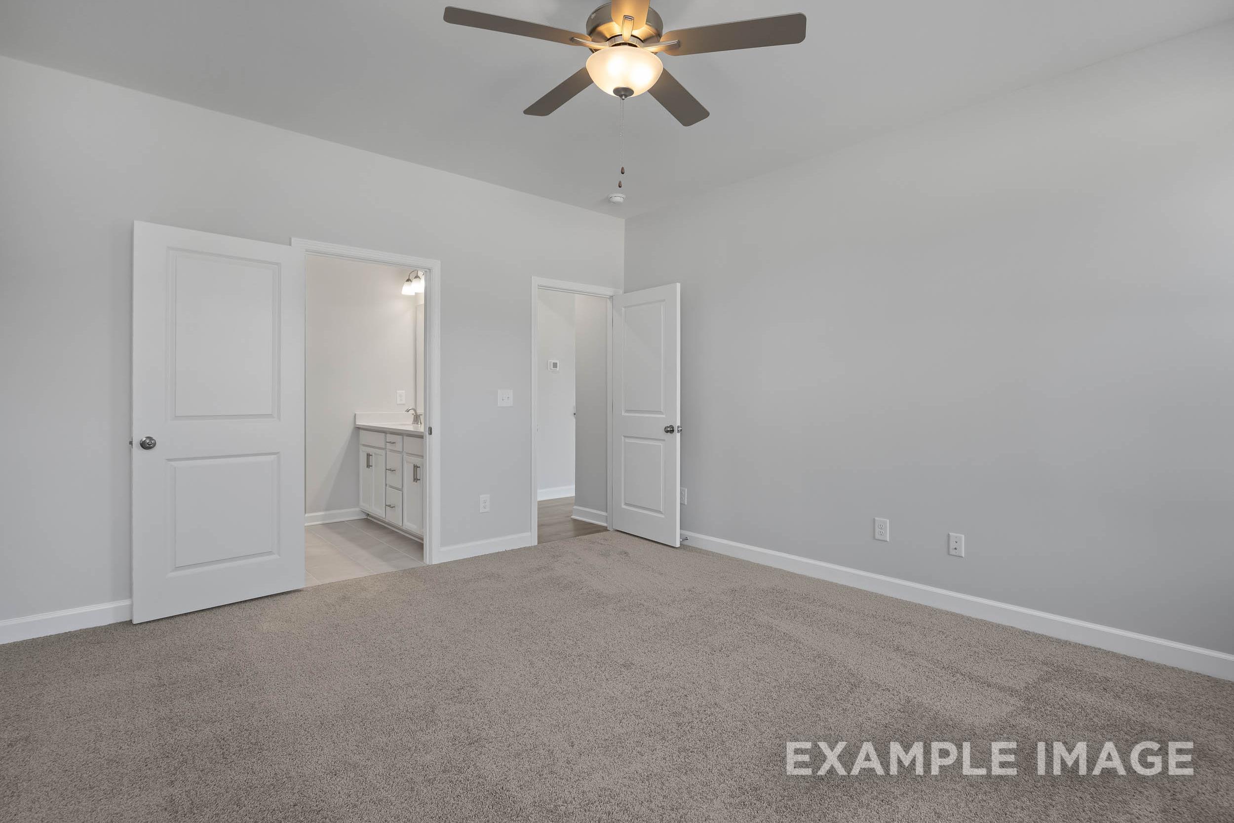 Spacious master bedroom in The Ash featuring open en-suite bathroom, ceiling fan, neutral gray walls, beige carpet