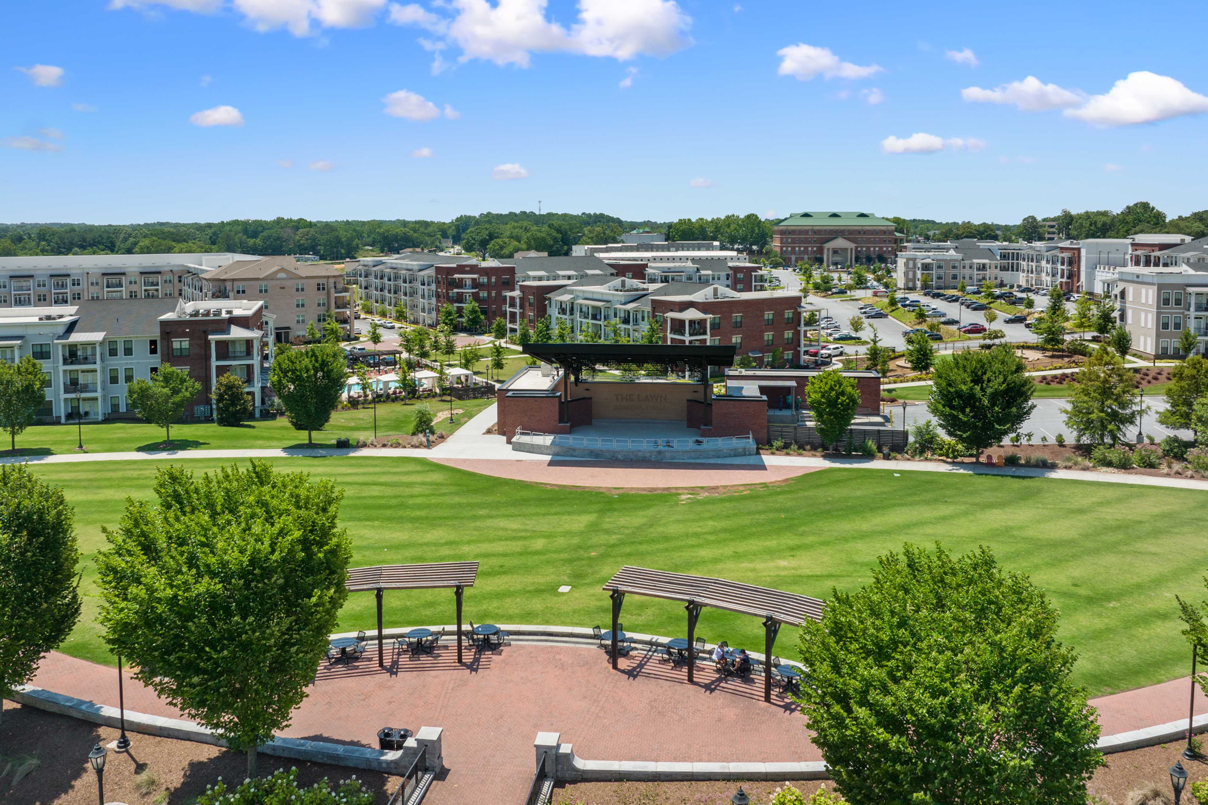 Community park featuring bandstand stage at Kelly Preserve in Loganville Georgia with green lawns modern apartments and trees