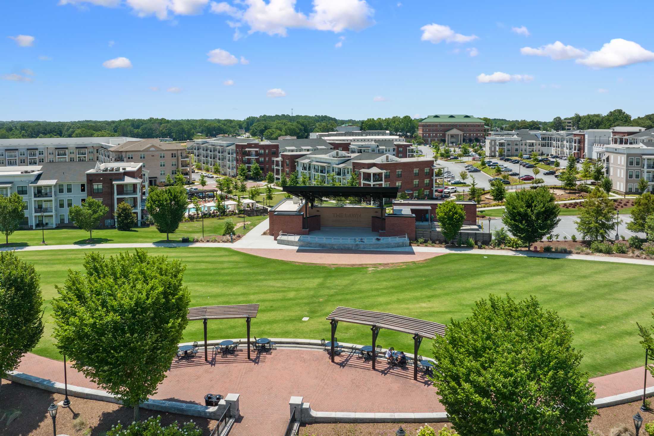 Community park featuring bandstand stage at Kelly Preserve in Loganville Georgia with green lawns modern apartments and trees