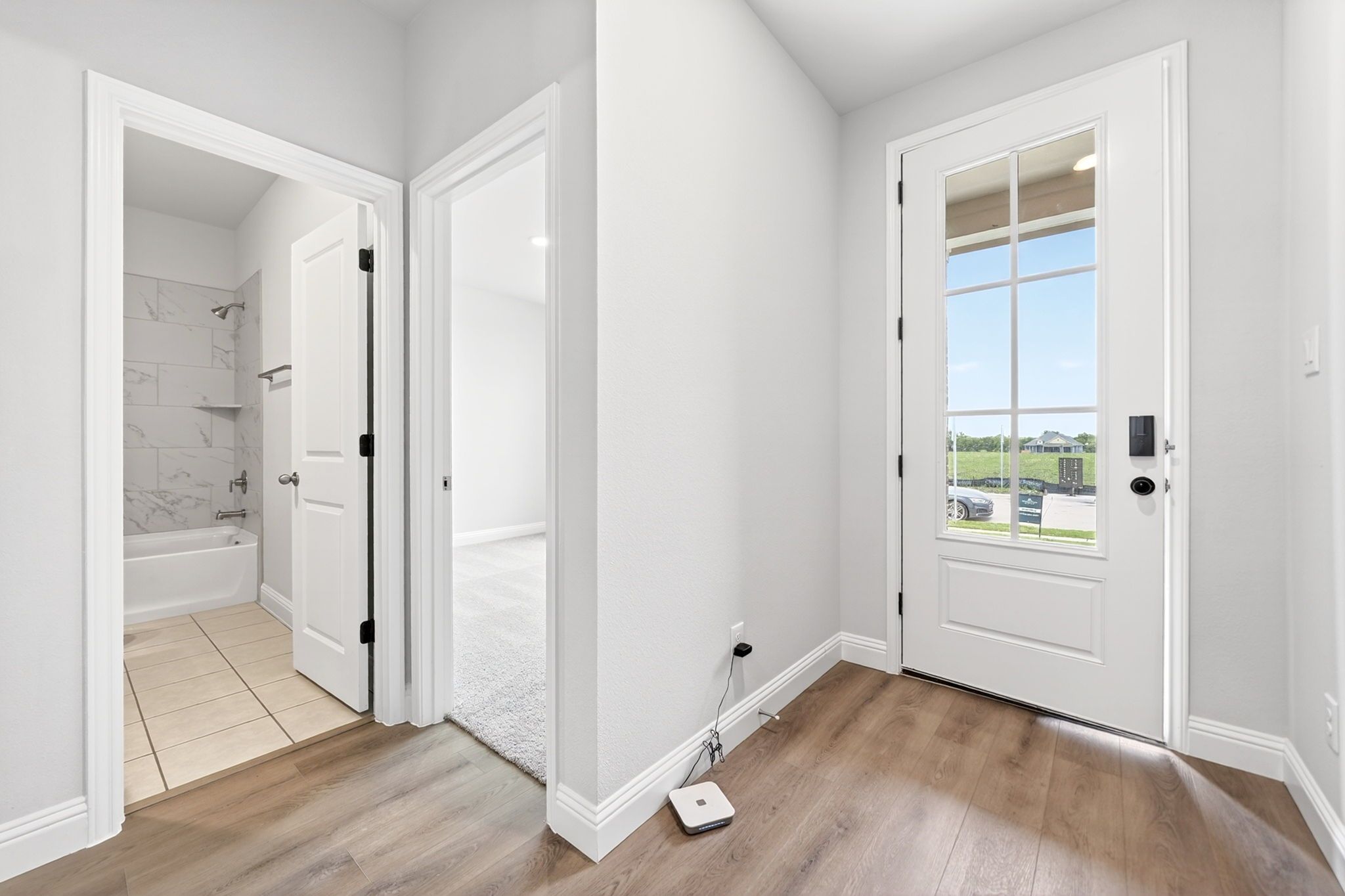 Entryway of The Redbud home in Josephine, Texas featuring wood-style flooring, a glass-paneled front door, and hallway.